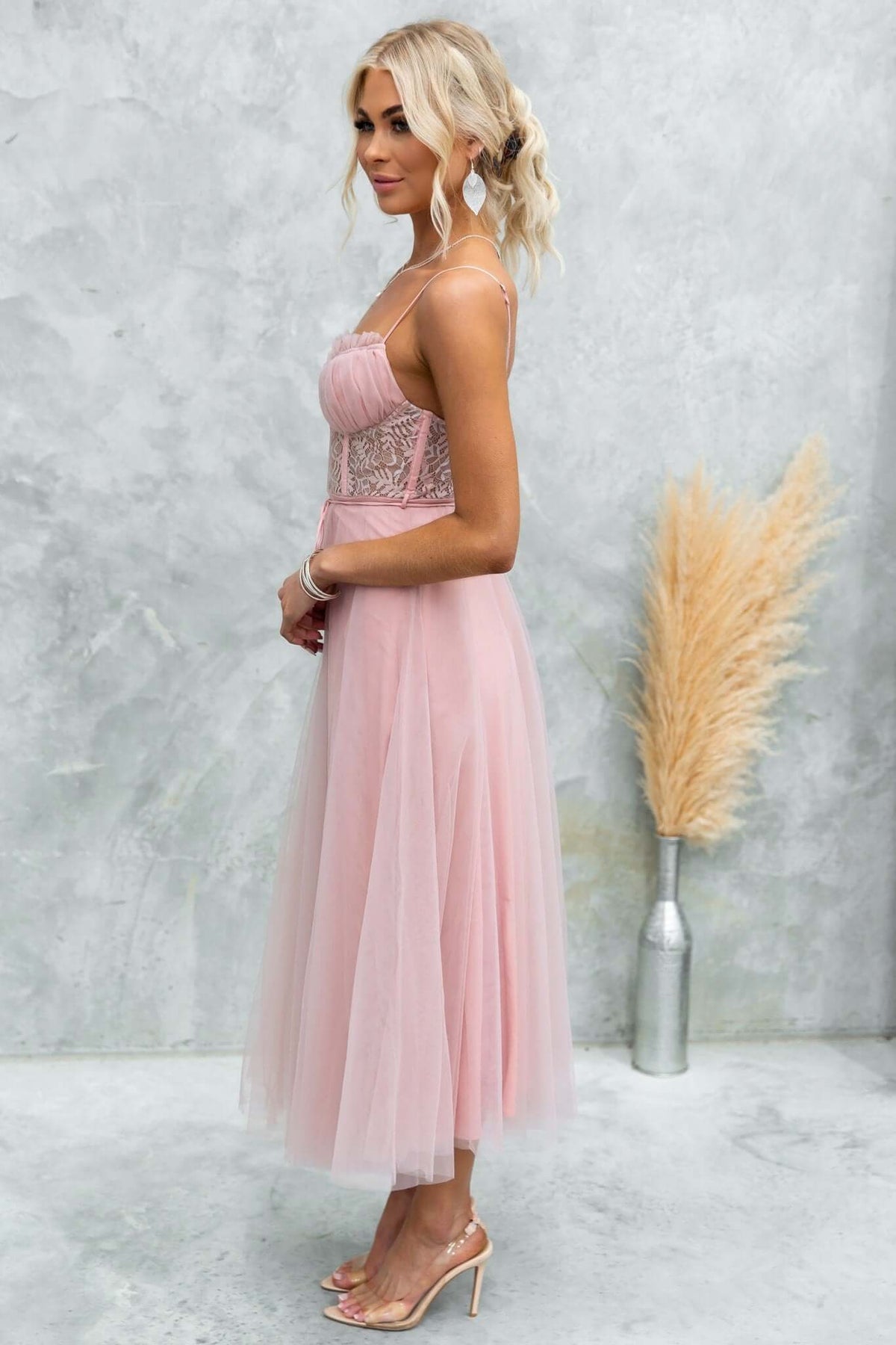 Side view of a model in a pink Wash Away Maxi Dress featuring lace detail and tulle fabric, styled with adjustable straps.