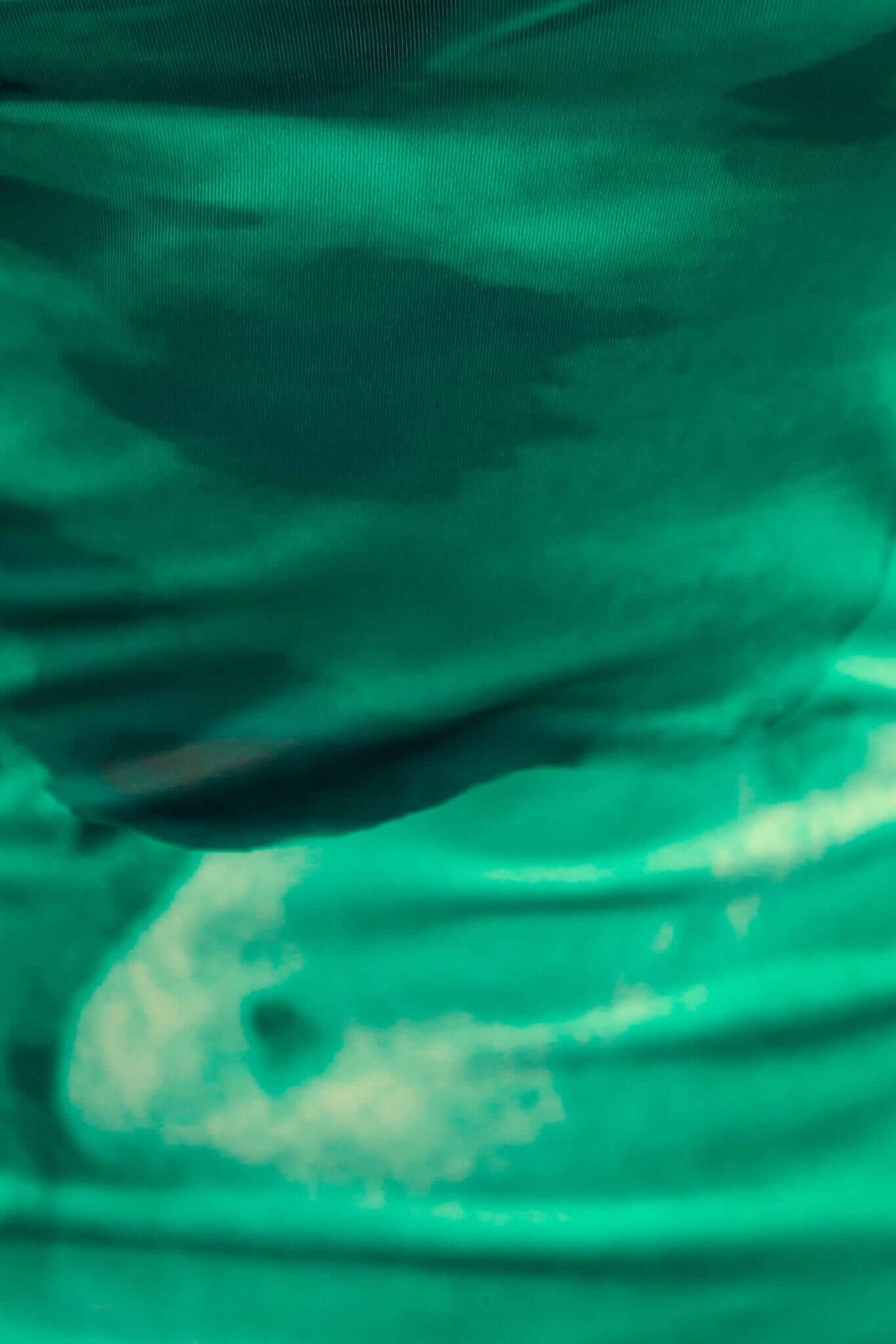 Close-up of green fabric texture, showcasing the stretch and smooth finish of the Dyxon Maxi Dress.