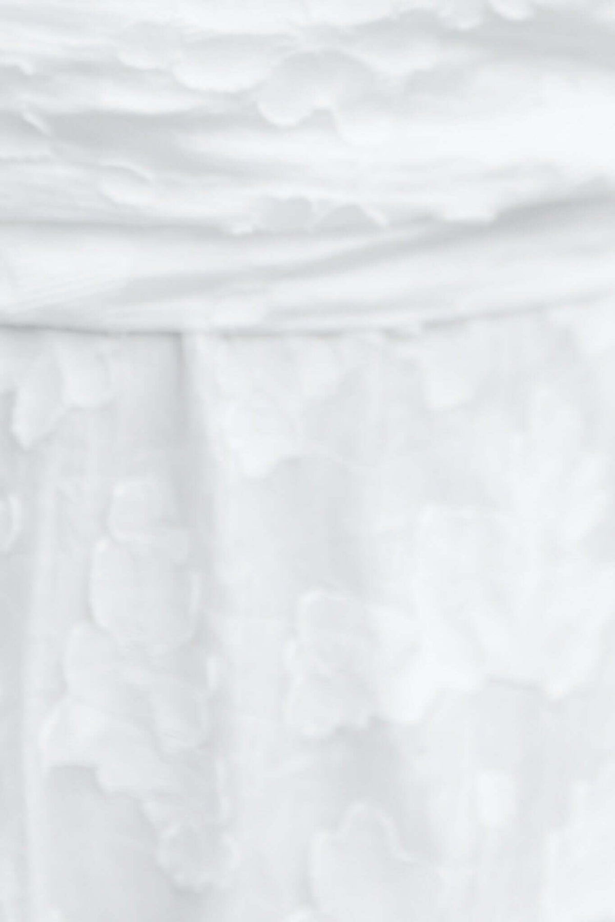 Close-up of the textured fabric of the Ivrea Maxi Dress in white, featuring delicate floral pattern.