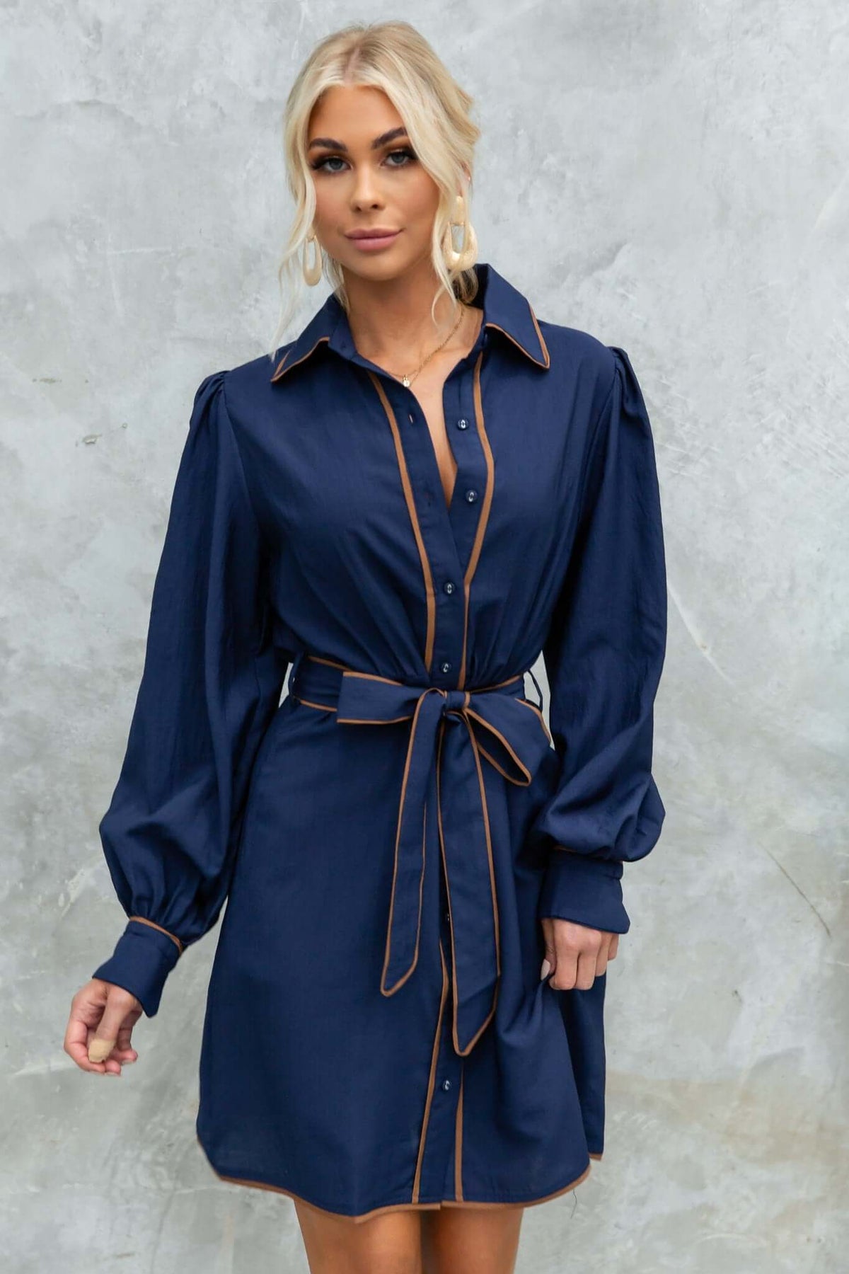 Model wearing the Pianolo Dress in navy, featuring a button-up front, elastic sleeves, and a removable tie.
