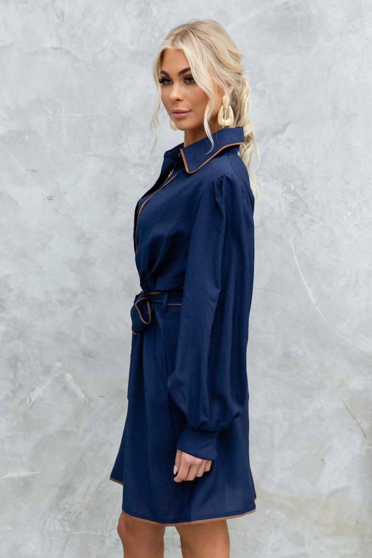 Model showcasing the Pianolo Dress, a navy button-up dress with a removable tie and elastic sleeves.