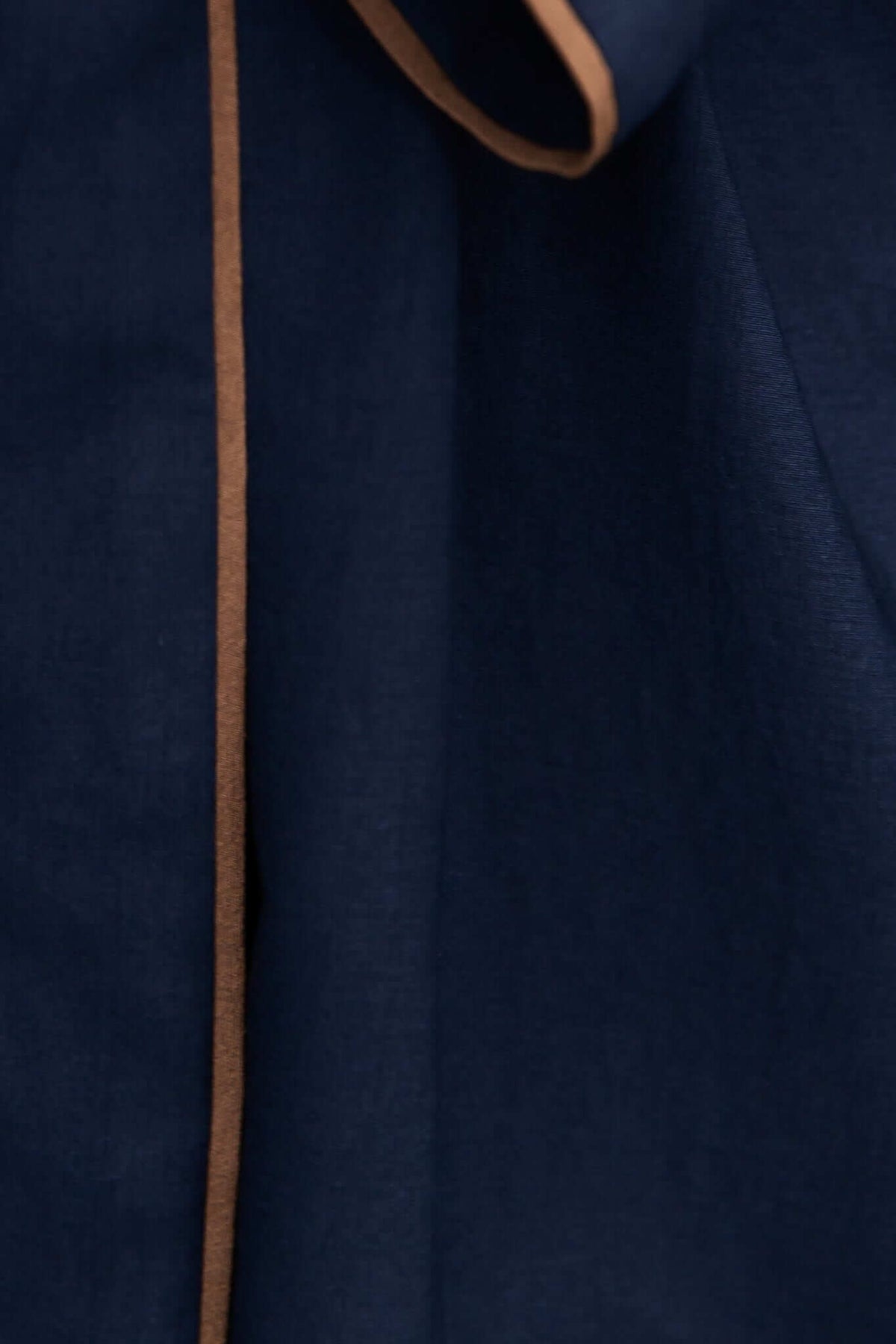 Close-up of Pianolo Dress showing navy fabric with contrasting brown trim detailing.