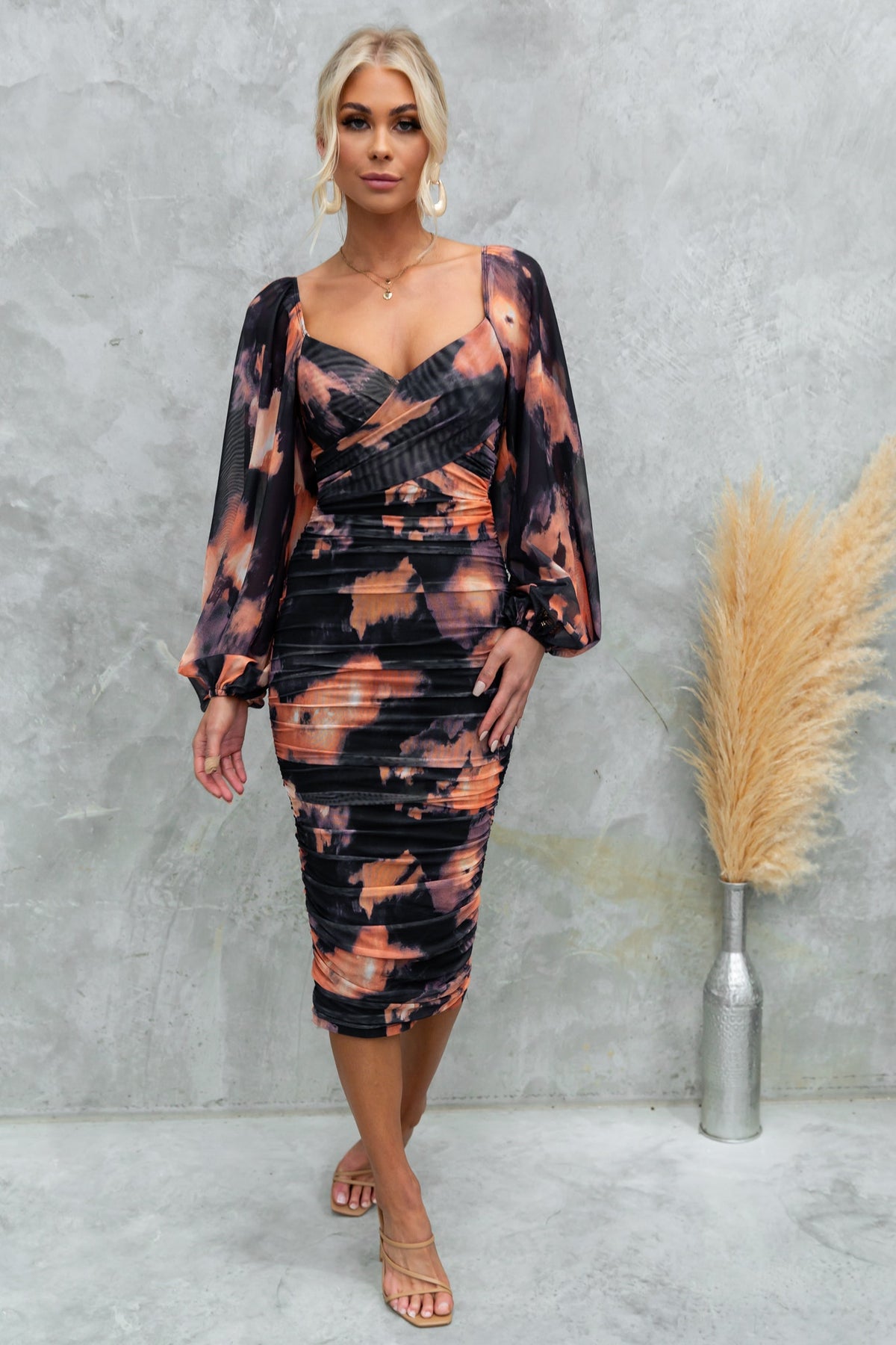 Stylish Evienne Midi Dress featuring a black and orange design with ruched mesh fabric and elegant puff sleeves.