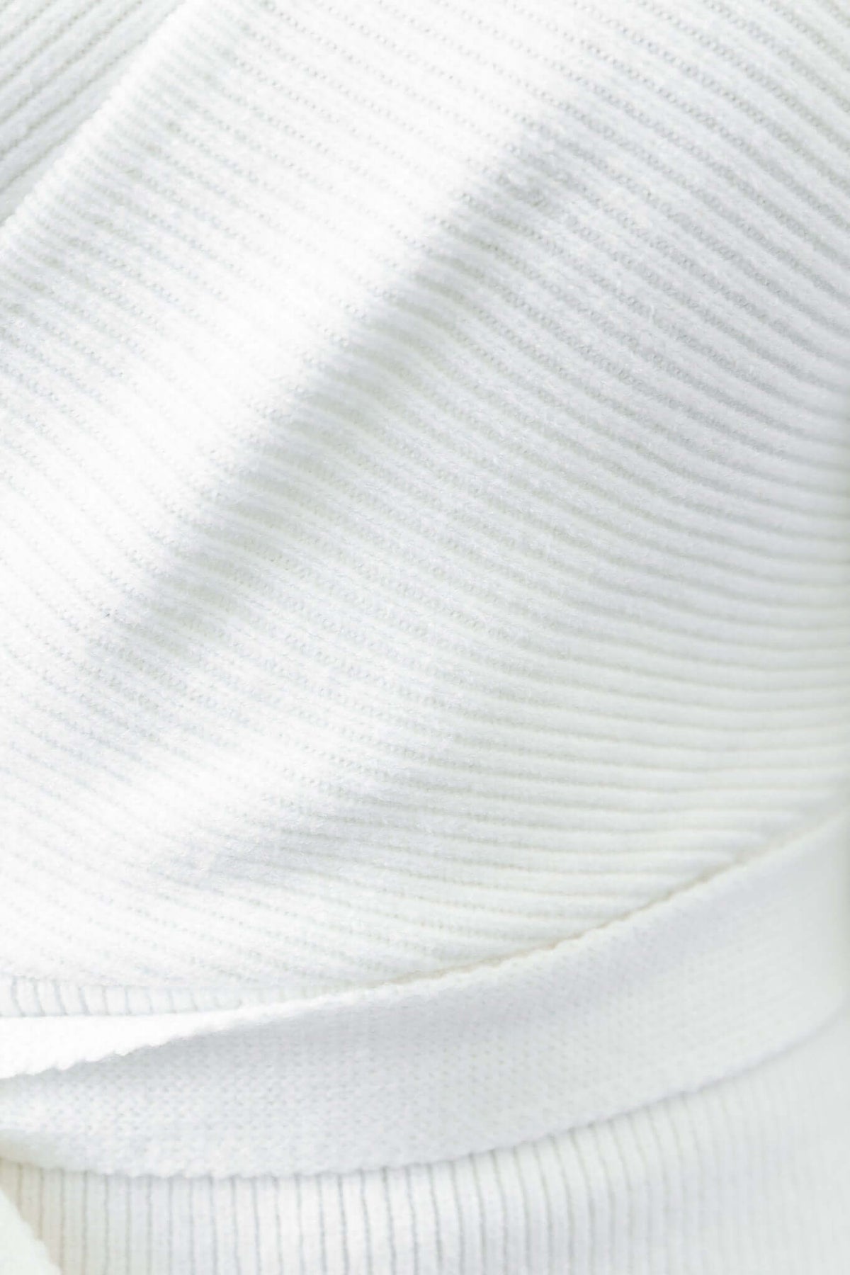 Close-up of the ribbed knit material texture of the white Nancy Dress, highlighting the V-neckline and removable tie.