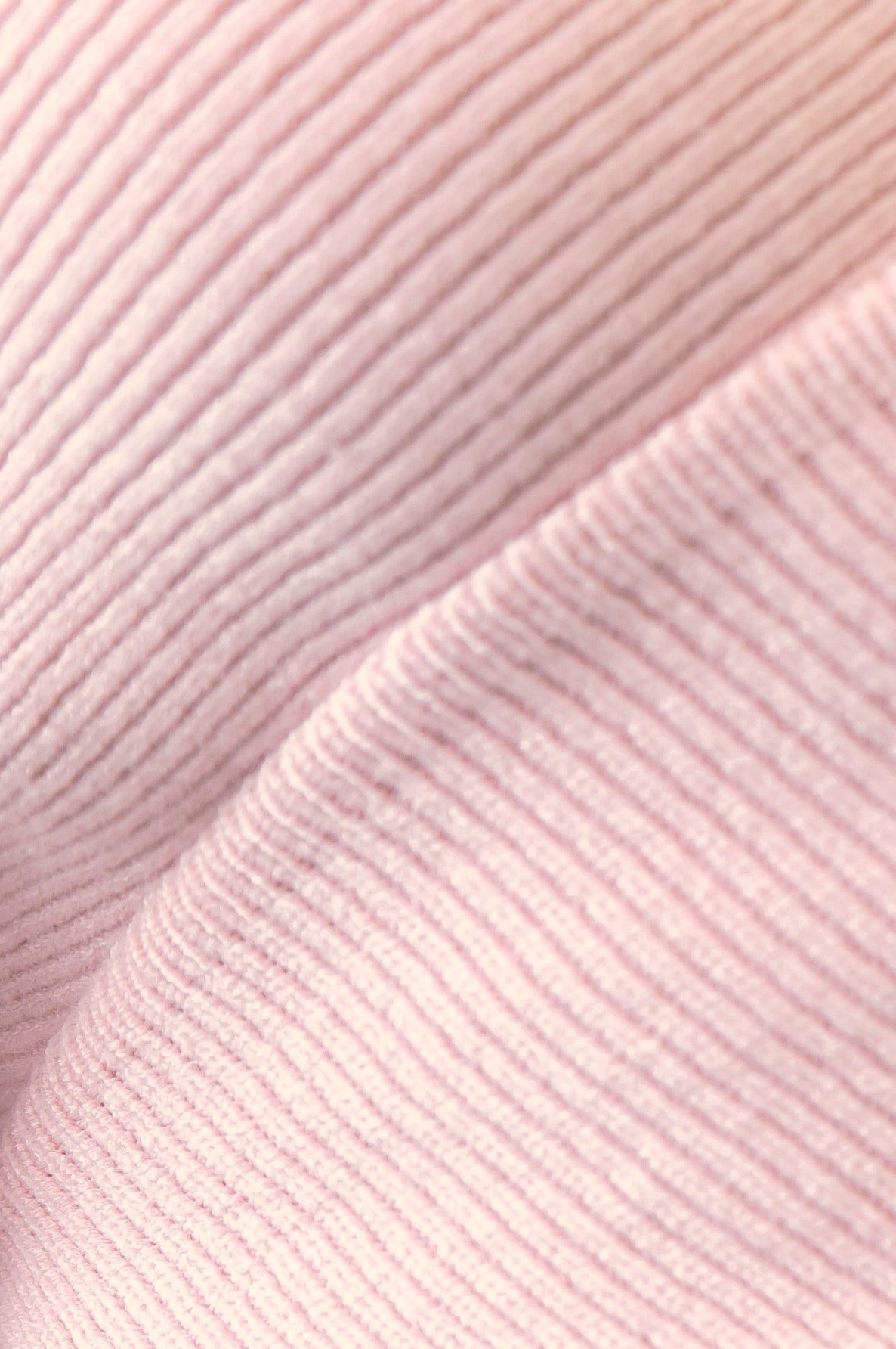 Close-up of ribbed pink knit fabric, showcasing its soft texture and stretch for the Nancy Dress.