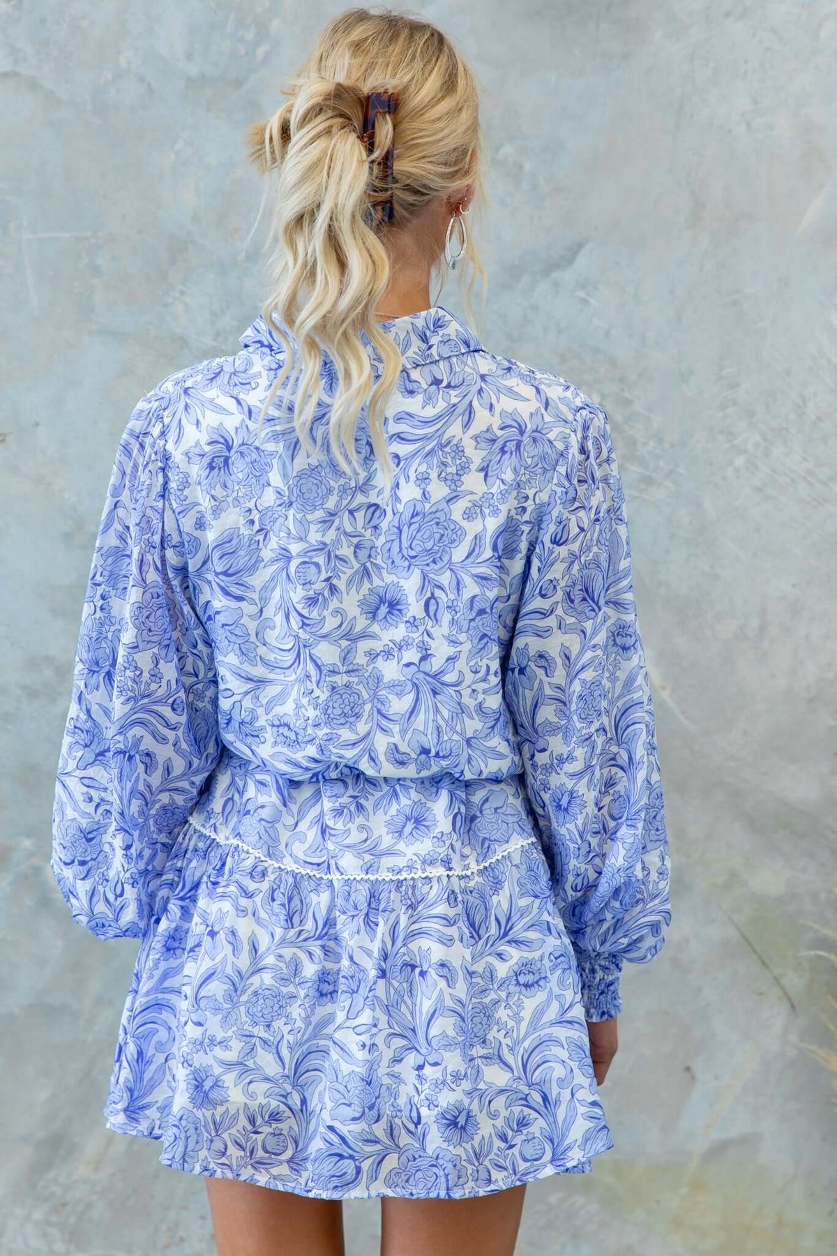 Back view of Alys Dress with floral pattern in blue, featuring a collar and elastic sleeves, perfect for casual wear.