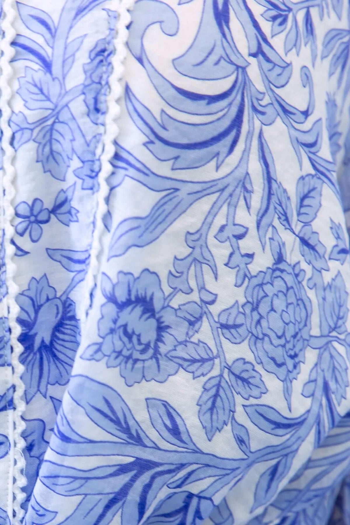 Close-up of blue floral print fabric with intricate details and lace trim for Alys Dress.