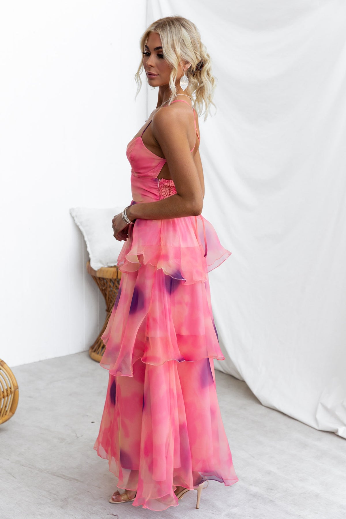Elinor Maxi Dress in pink chiffon with ruffle skirt, featuring adjustable straps and side zip, styled for a summer look.