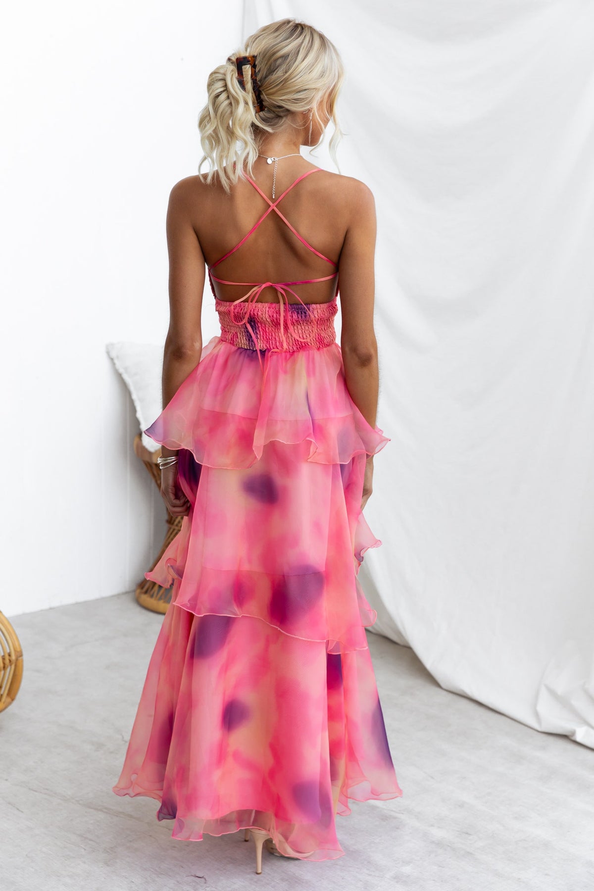 Back view of Elinor Maxi Dress in pink chiffon with ruffle skirt and adjustable tie straps, showcasing a flowy design.
