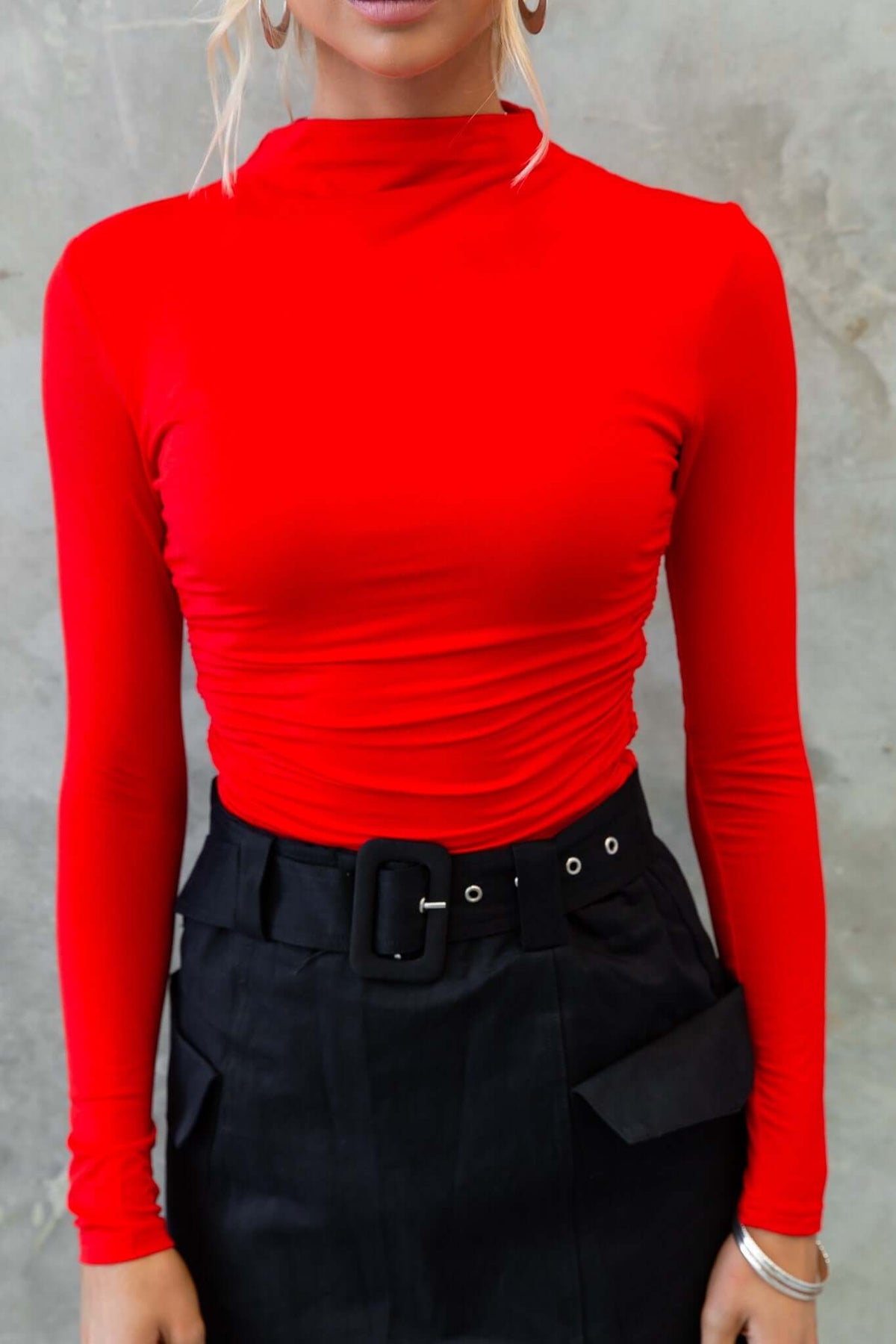 Red Rumba Top with high neckline and long sleeves, styled with a black belted skirt, perfect for casual or dressy occasions.