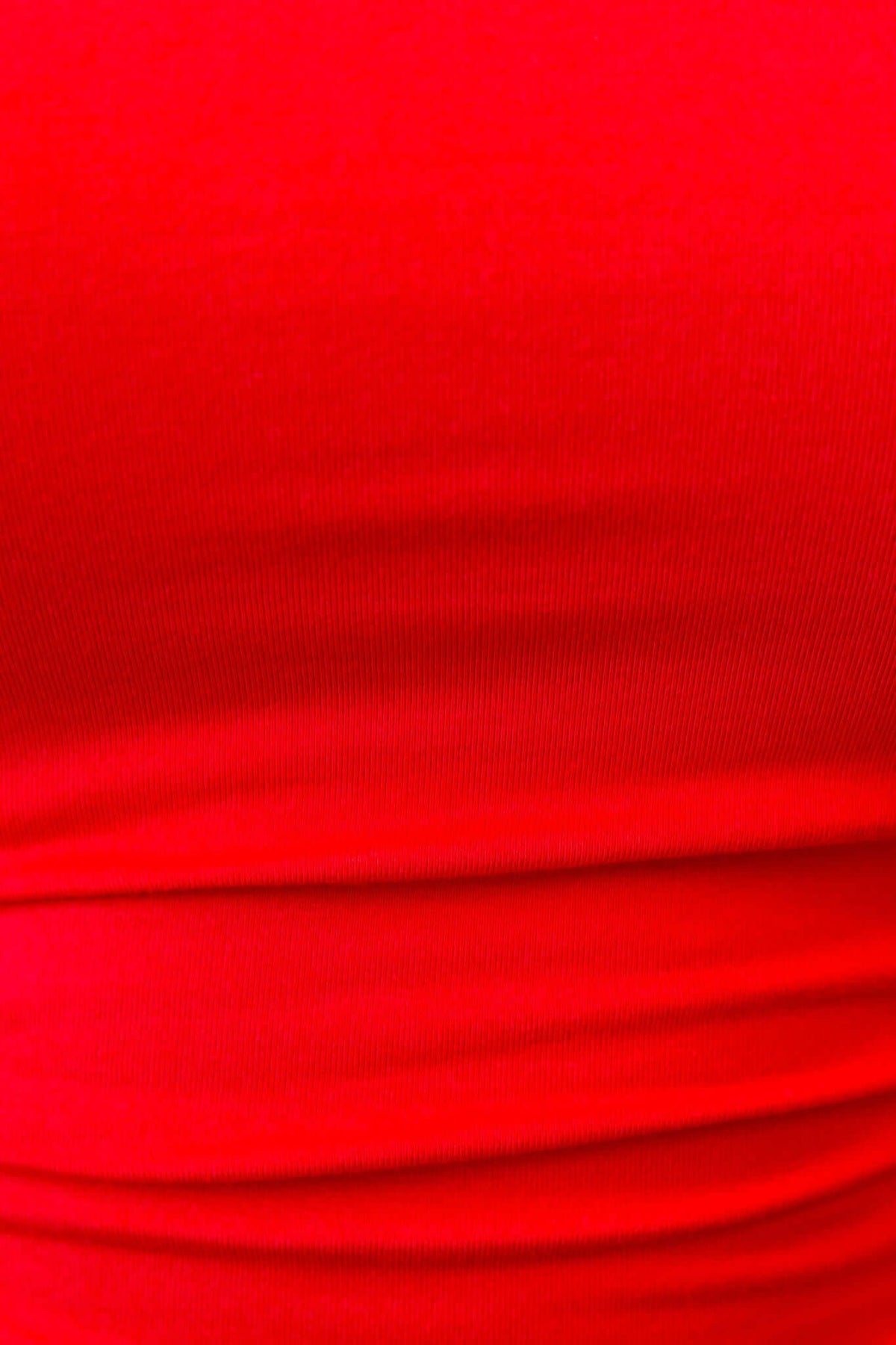 Close-up of vibrant red stretchy fabric from Rumba Top, showcasing the smooth texture and rich color.