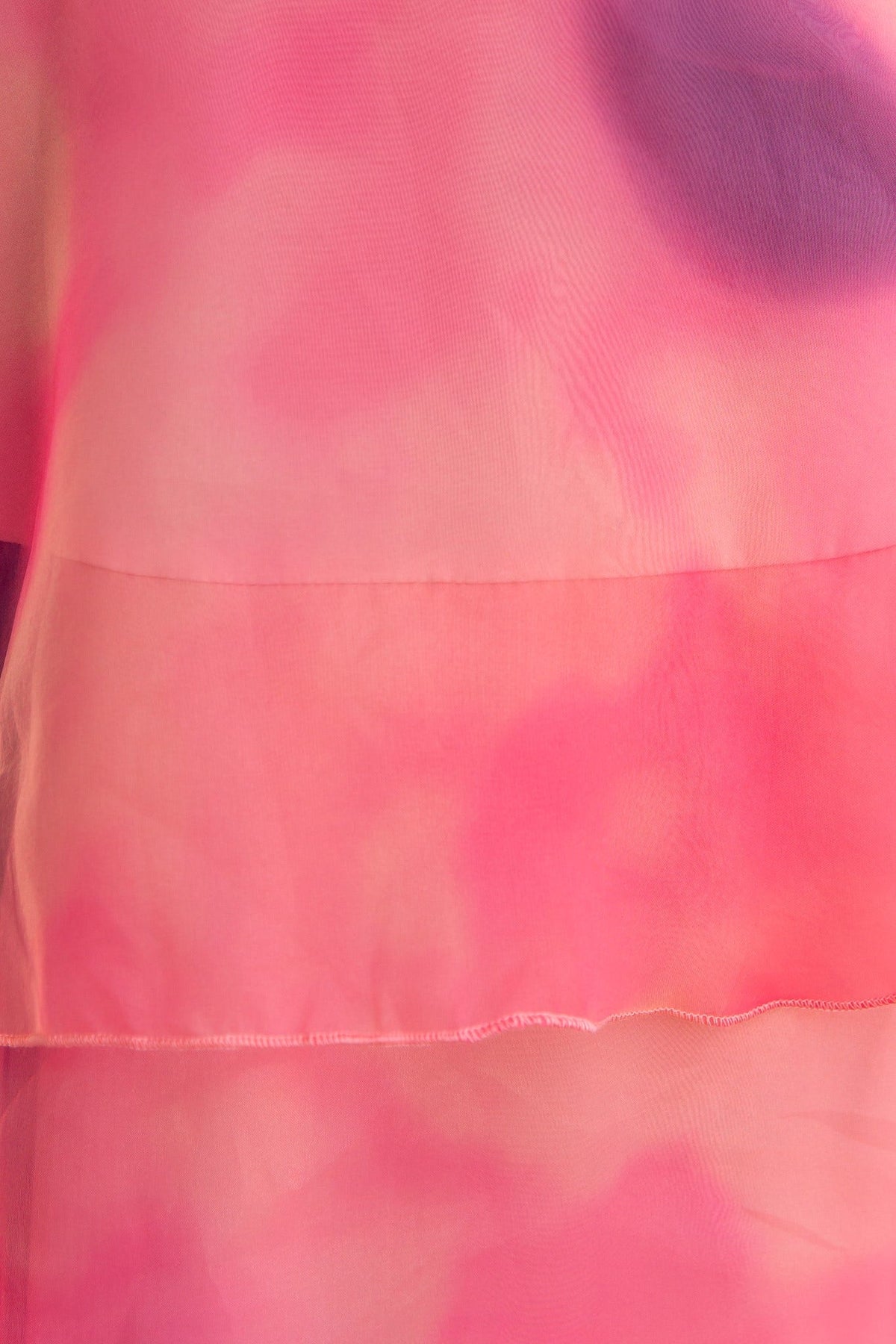 Close-up of the Elinor Maxi Dress in a pink chiffon fabric with a ruffle detail and colorful watercolor pattern.