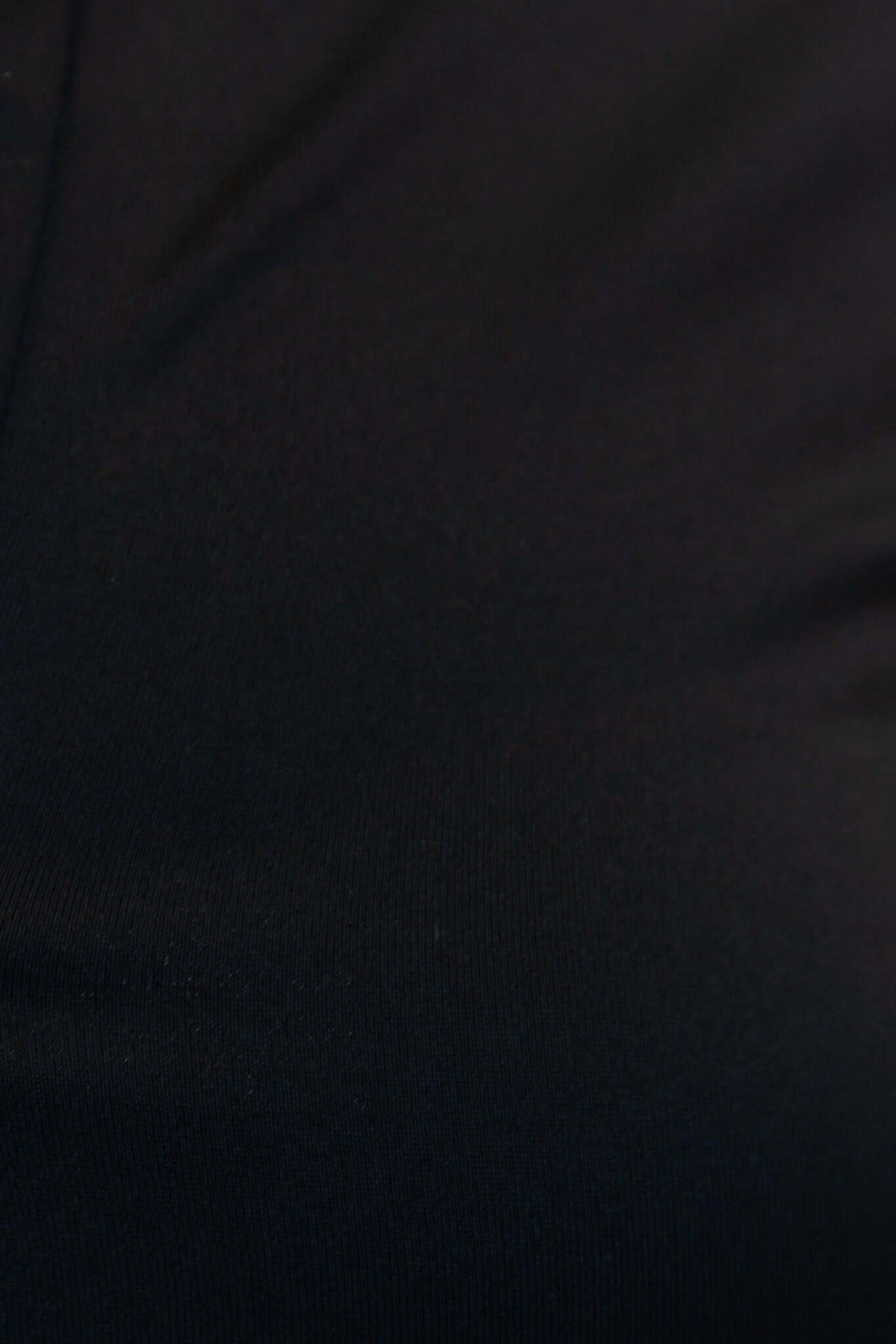 Close-up of black stretchy fabric of Unfair Bodysuit, highlighting its smooth texture and quality material.