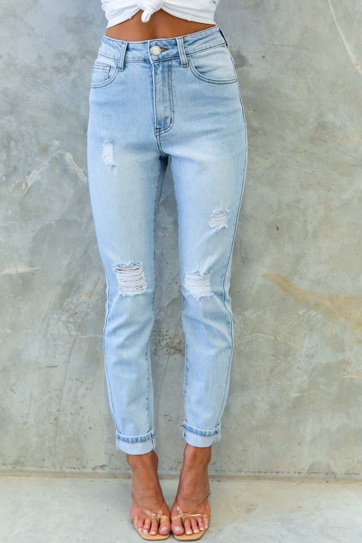 Stylish amber jeans with a mid-high waist, distressed rips, and front/back pockets, paired with a casual top.