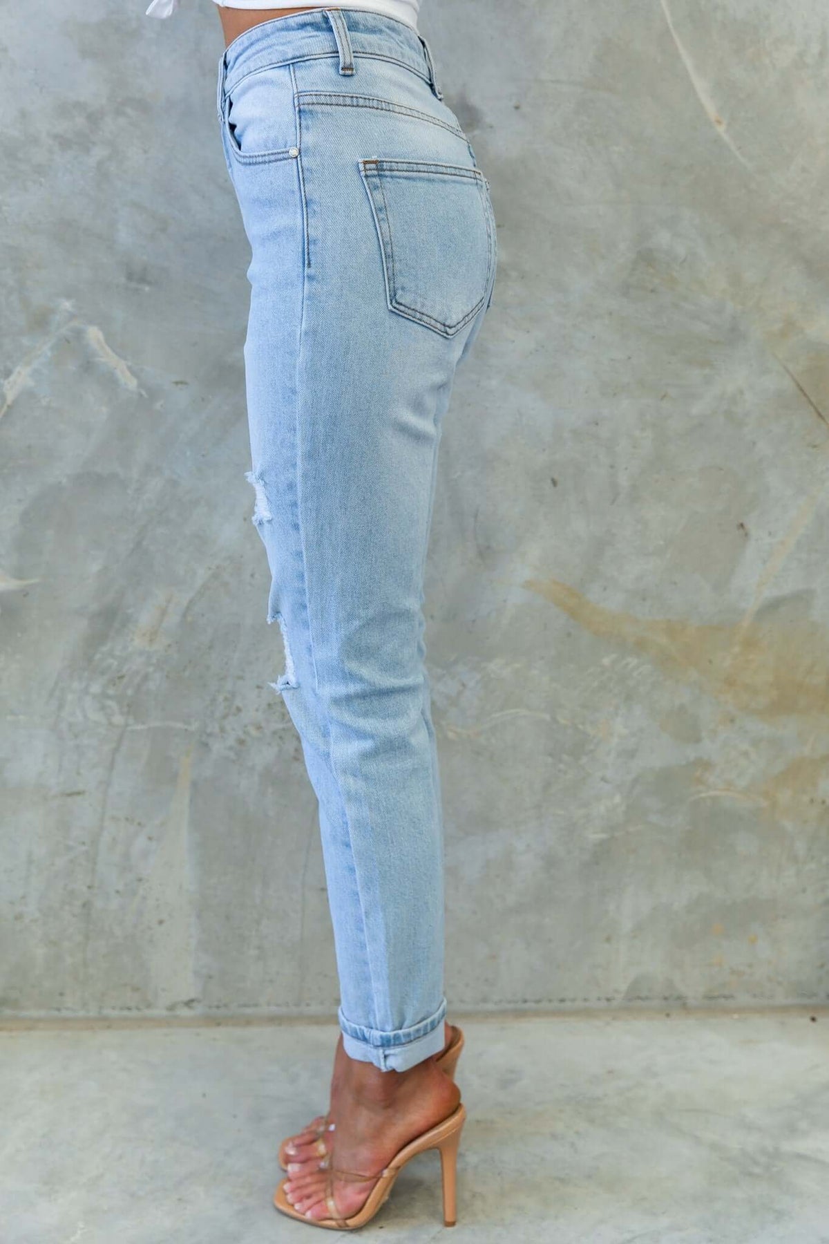 Side view of Amber Jeans featuring a mid-high waist, distressed rips, and a fitted silhouette.