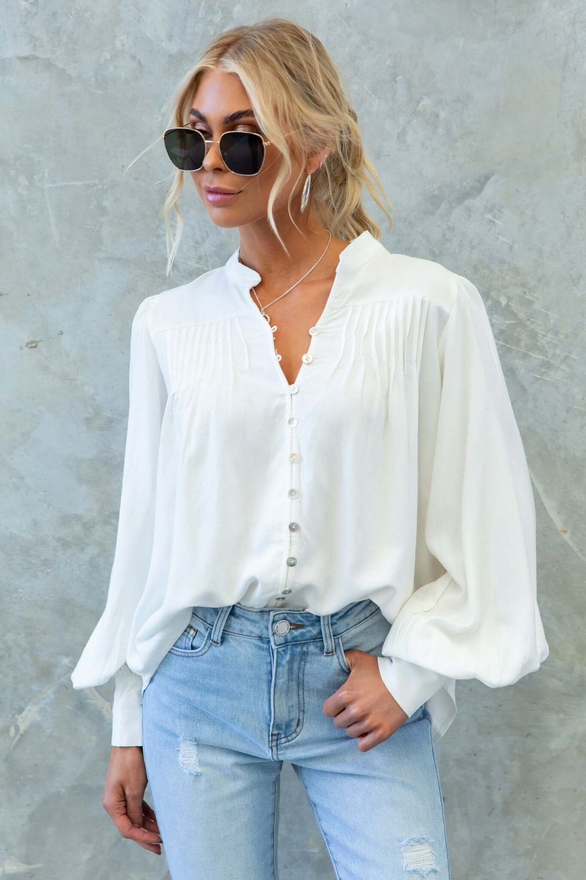 Model wearing a white Brunie shirt with button-up front and relaxed fit, styled with denim jeans and sunglasses.