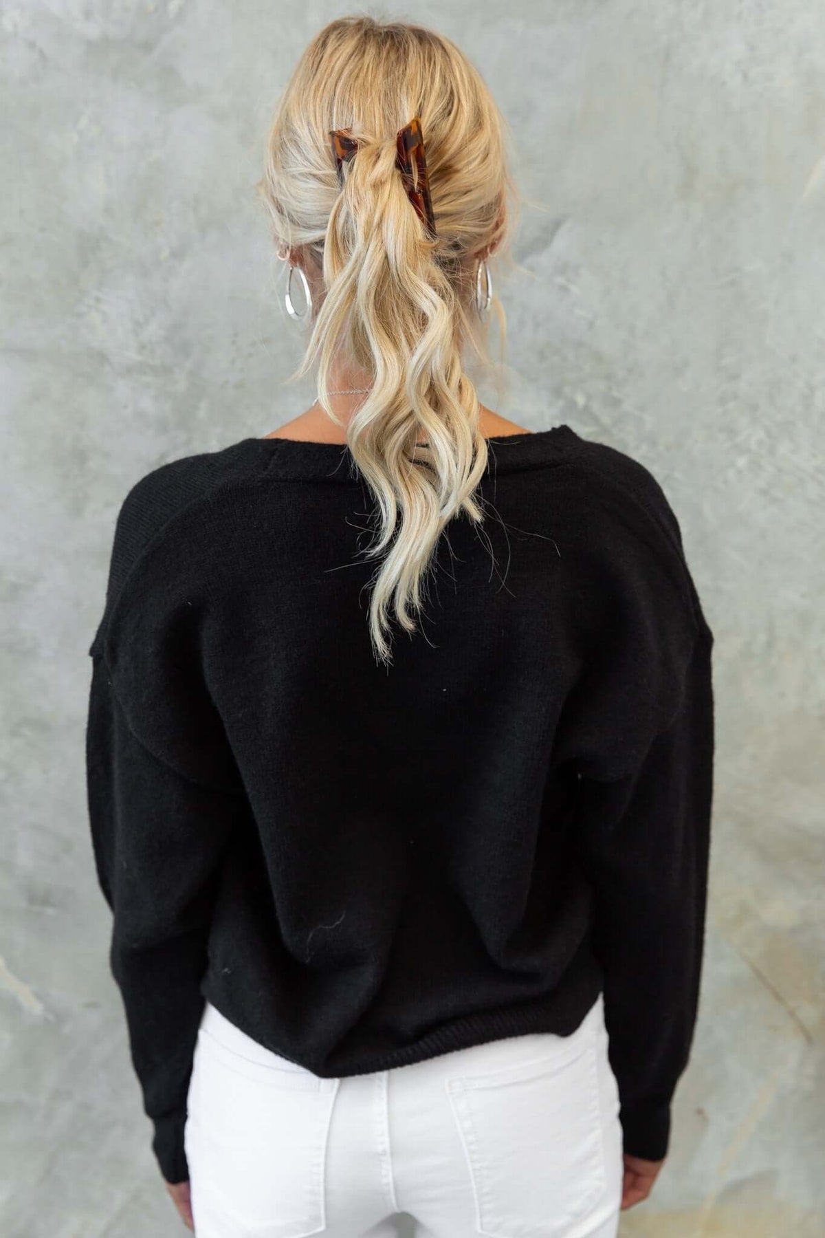 Model wearing a black Varian cardigan from the back, featuring a relaxed fit and knit material.