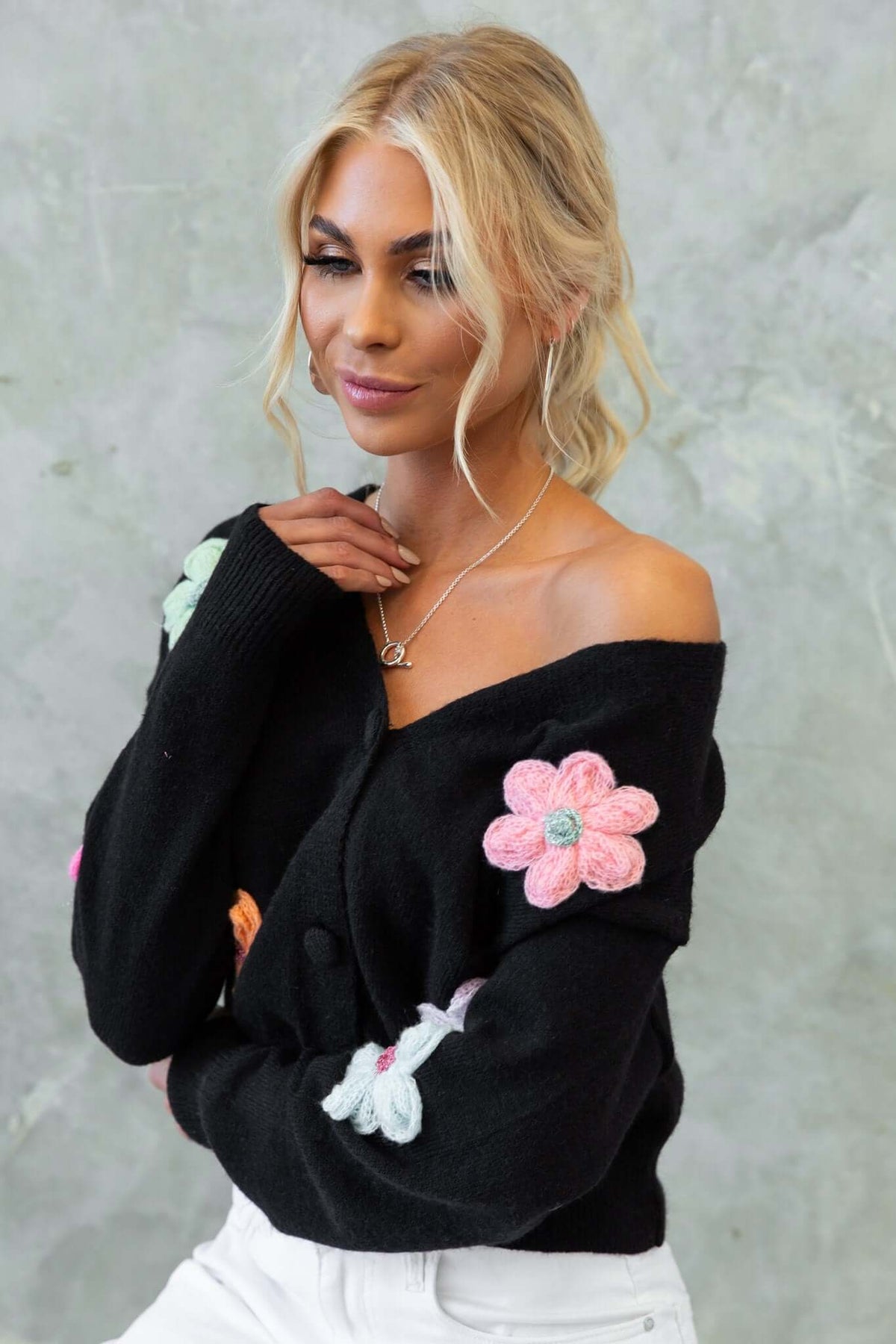 Model wearing Varian Cardigan in black with floral embroidery, showcasing a V-neckline and button-up front.