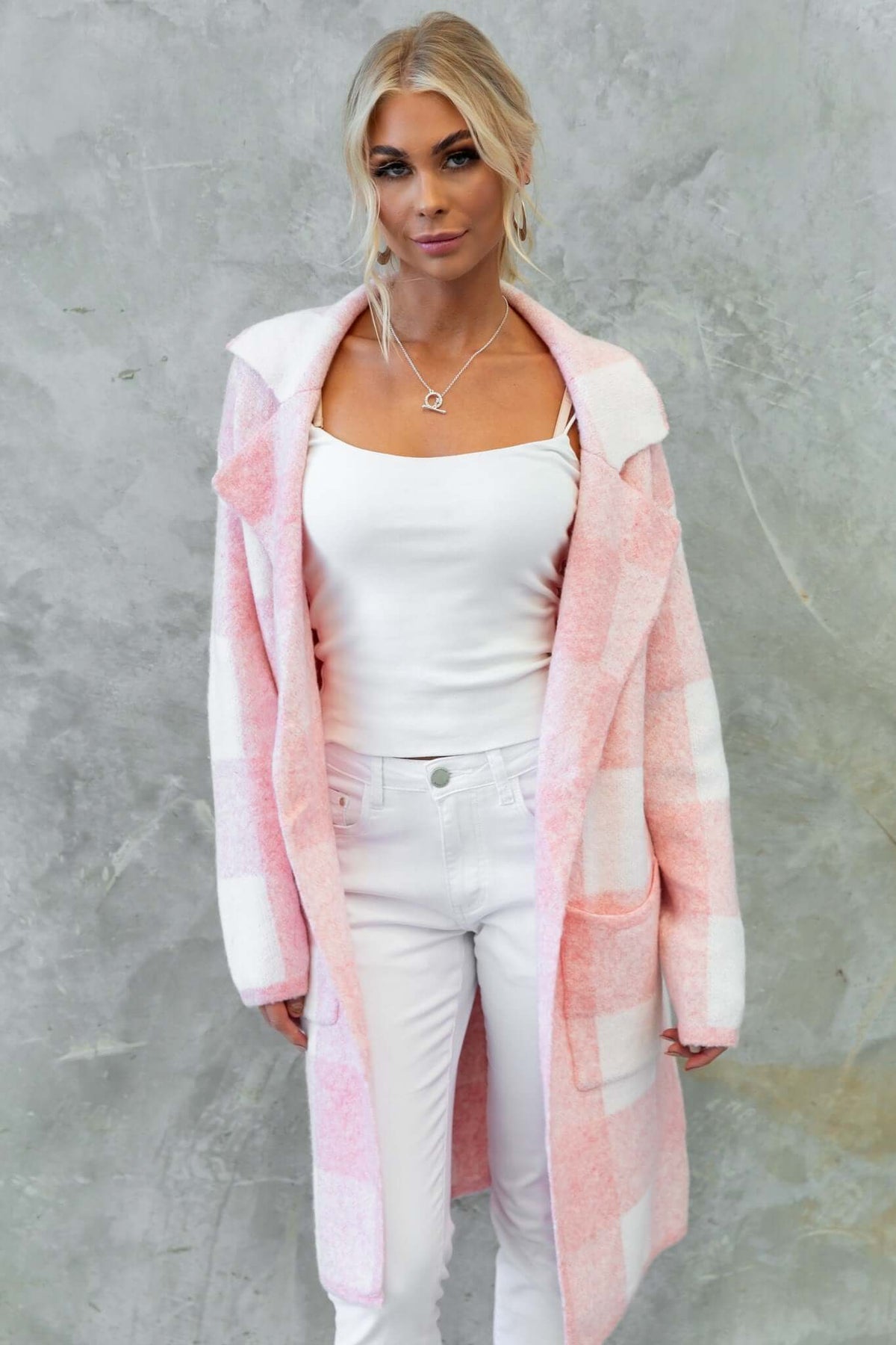 Model wearing a longline Fatale Cardigan in pink and white checks, styled with a tank top and white jeans.