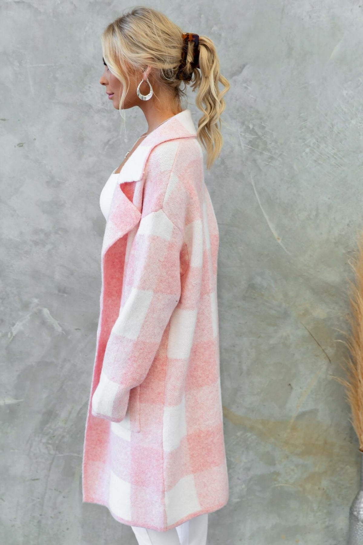 Profile view of the Fatale Cardigan in pink and white checkered knit, featuring a longline fit, collar, and pockets.