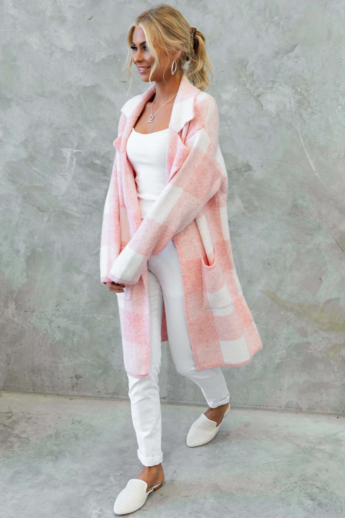 Model wearing a longline pink and white striped Fatale Cardigan with pockets, styled with a white top and jeans.