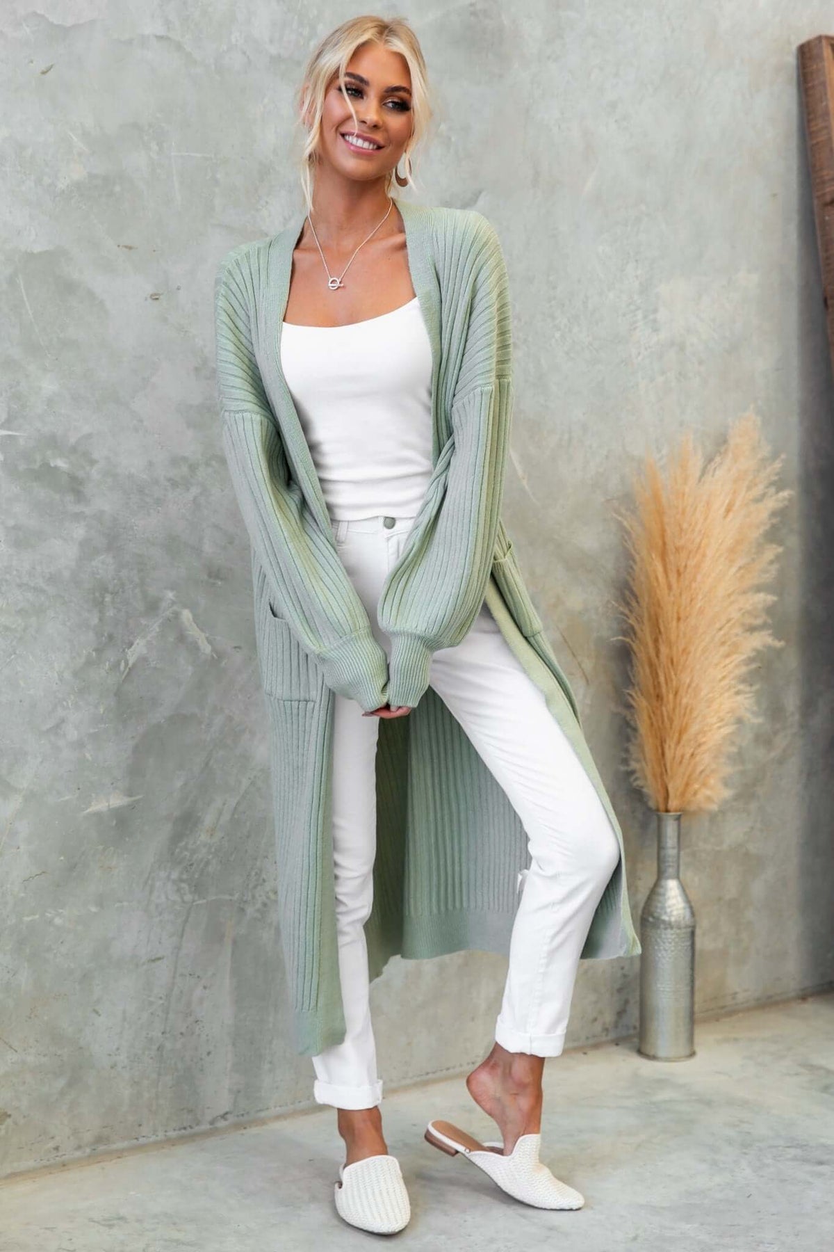 Fano cardigan in light green worn over a white top and pants, paired with stylish slippers, ideal for casual layering.