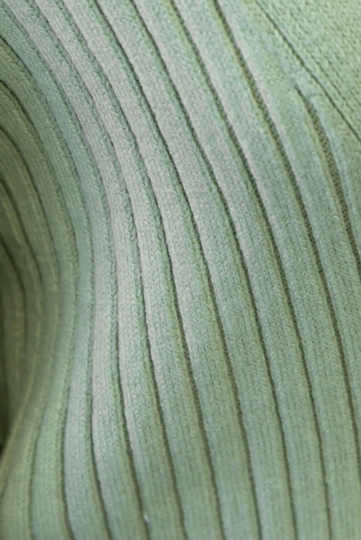 Close-up of textured green knit fabric showing vertical ribbing, perfect for a cozy cardigan style.