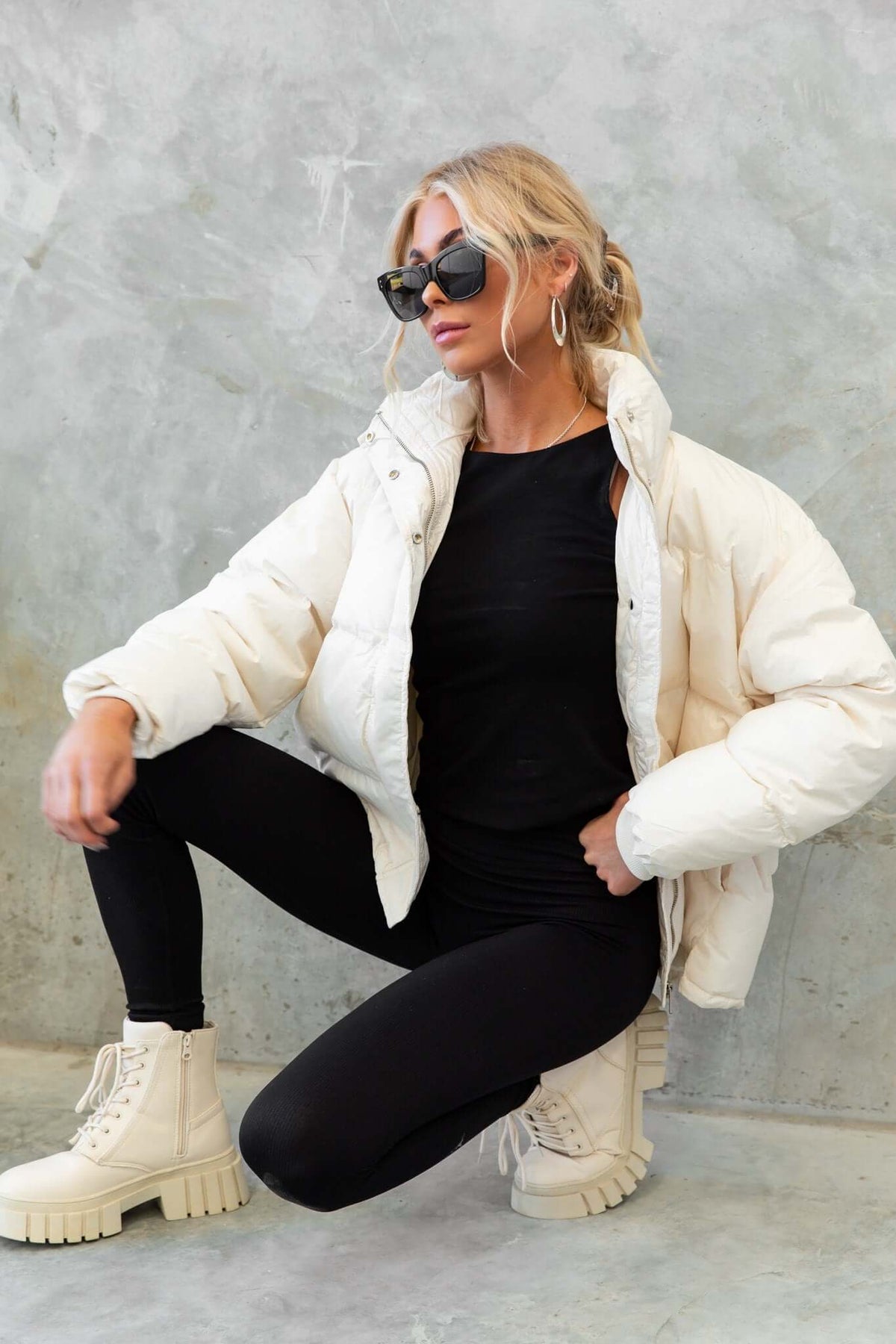 Model wearing a cream Cooper Puffer Jacket with high neckline, styled with black leggings and chunky boots.