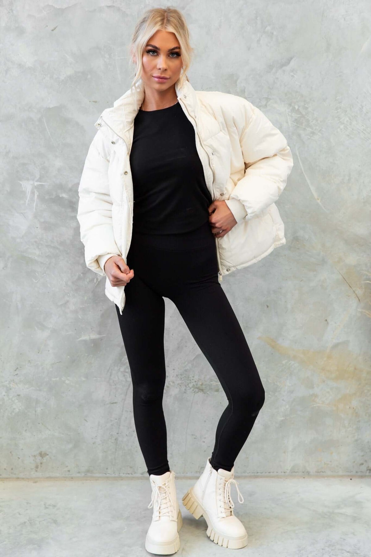 Model wearing a white Cooper Puffer Jacket styled with black leggings and boots, showcasing its cozy and casual look.