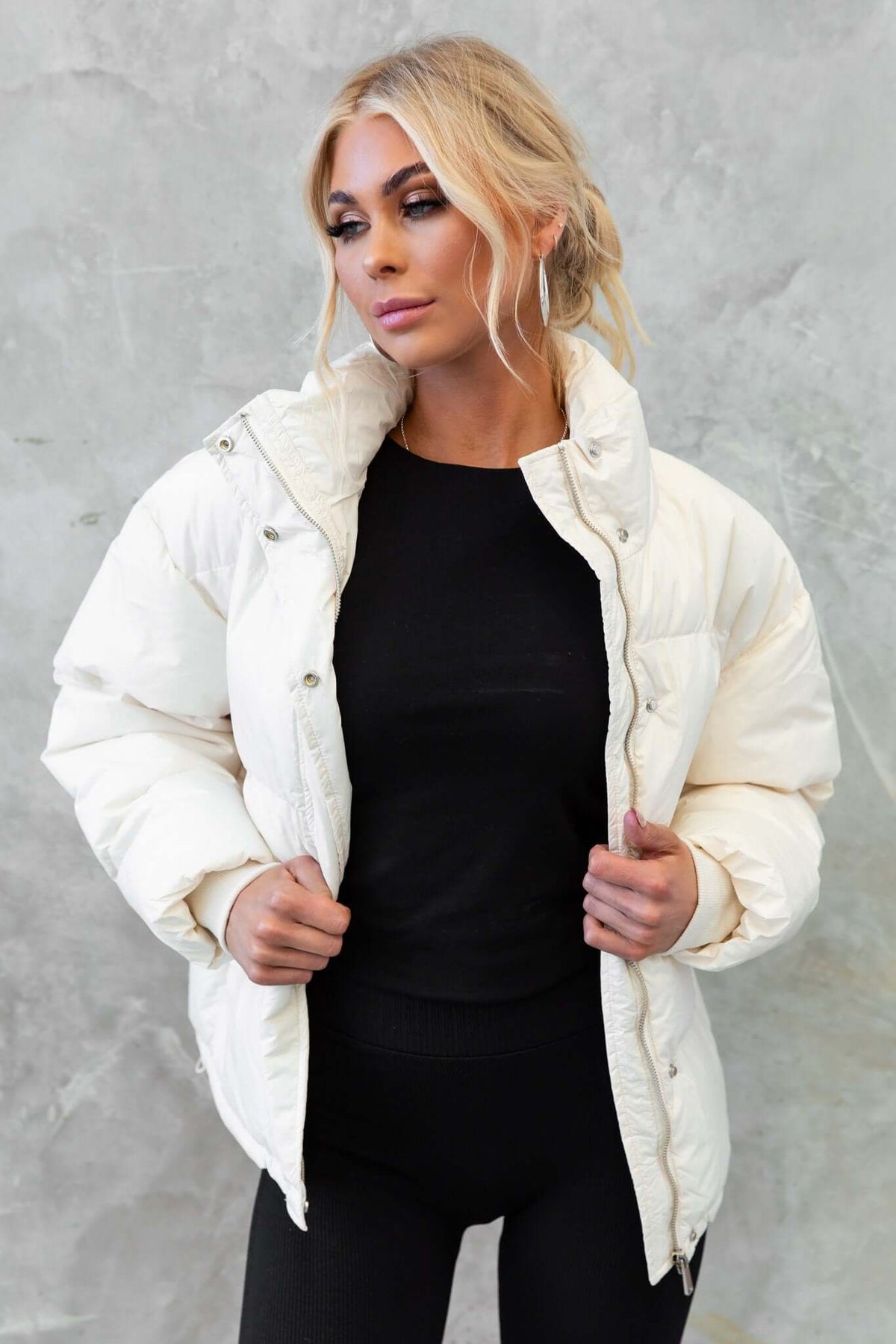 Model wearing a stylish white Cooper Puffer Jacket with high neckline and button closure, paired with a black top.