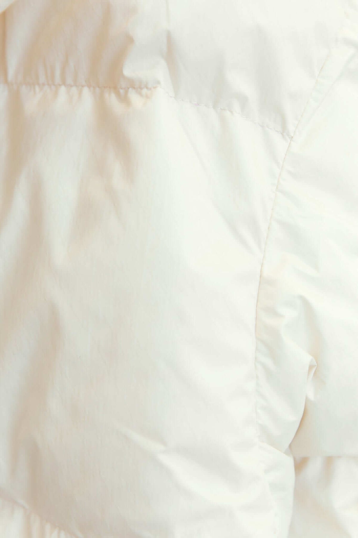 Close-up of the soft white fabric of the Cooper Puffer Jacket, showcasing its quilted texture and high-quality material.