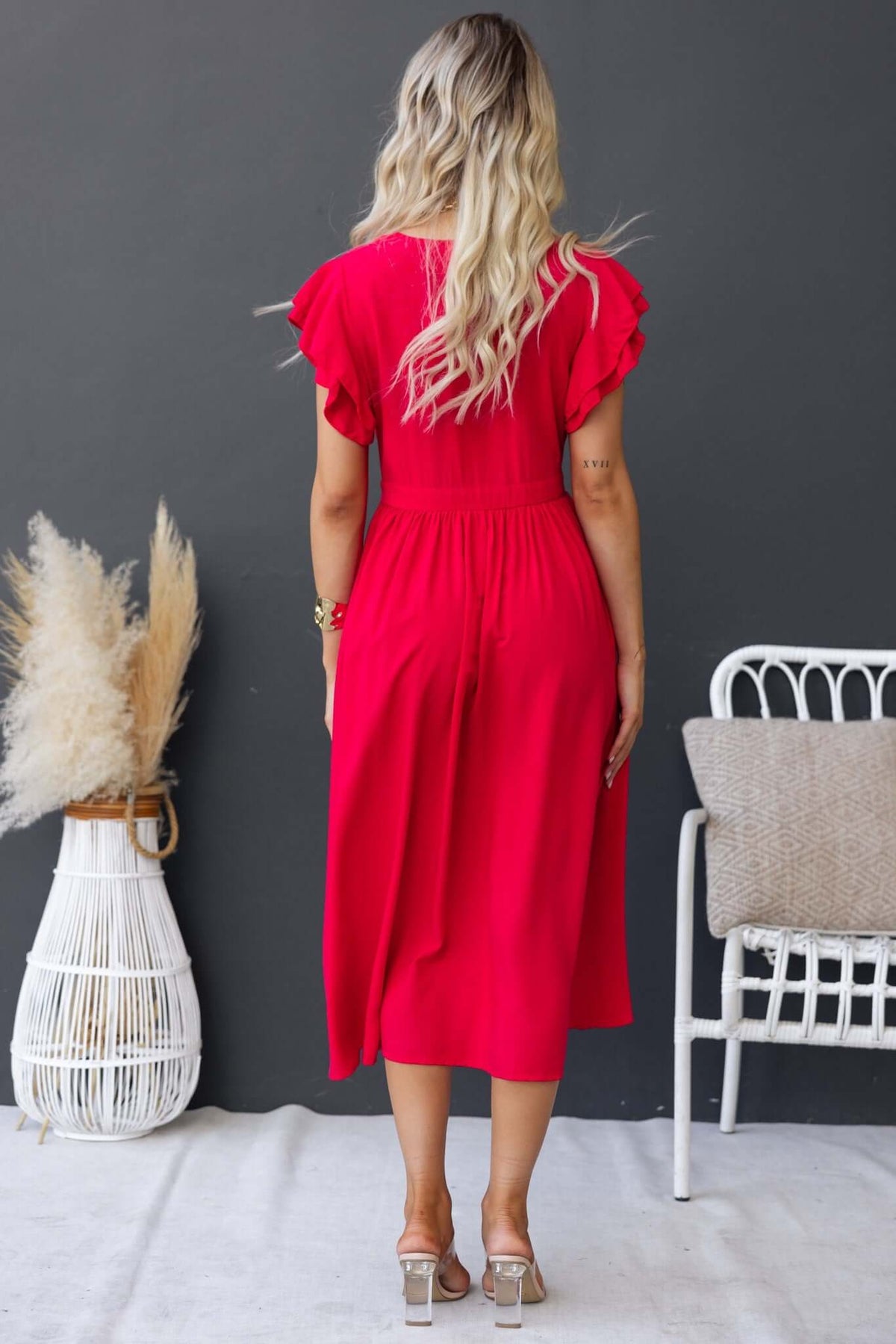 Back view of a woman wearing a red Joelle Midi Dress with ruffled sleeves, showcasing a stylish and comfortable design.