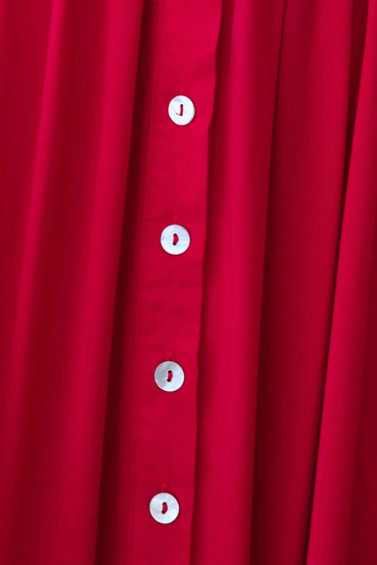 Close-up of the Joelle Midi Dress featuring a button-up front and vibrant red fabric.