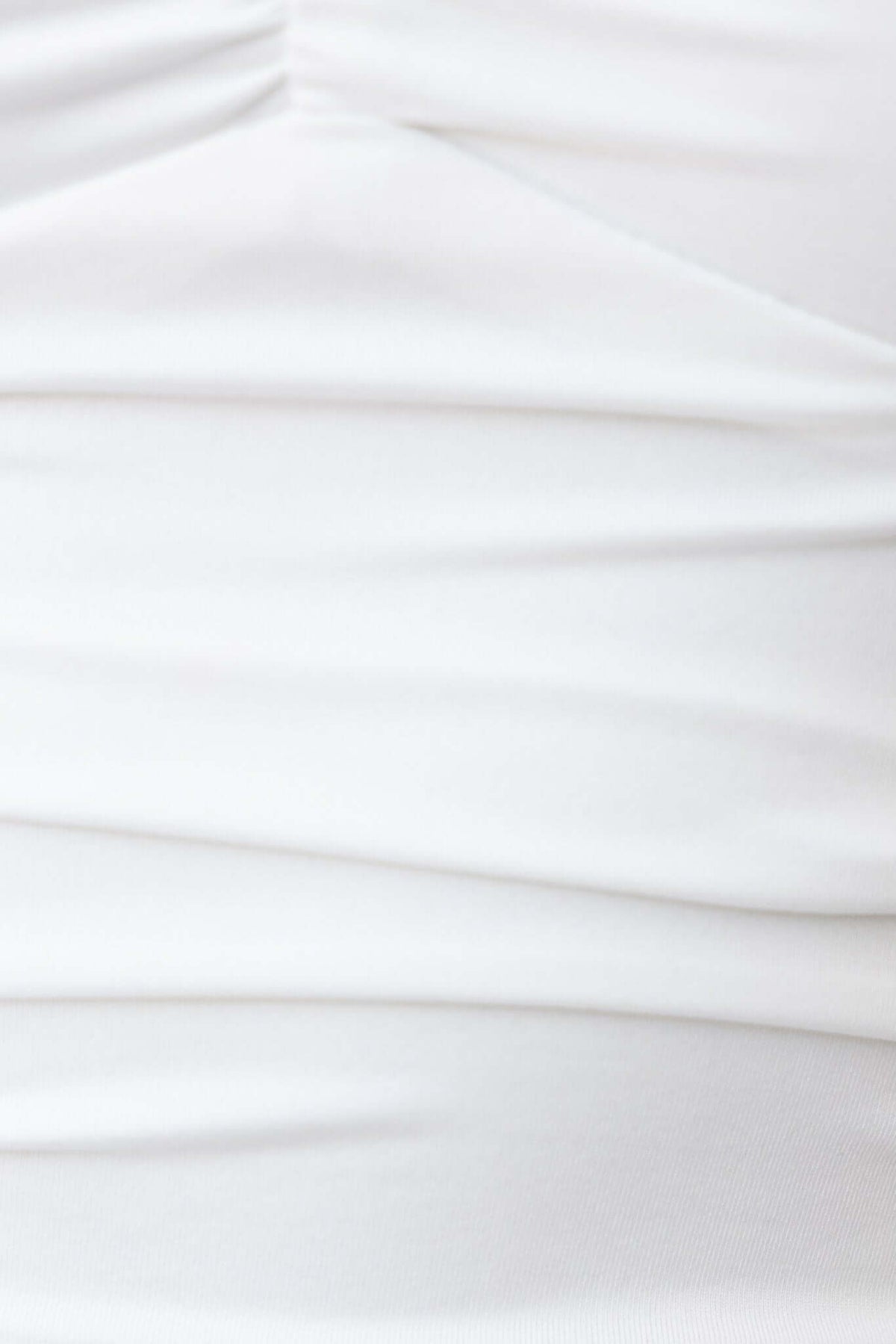 Close-up of white Clyne Bodysuit fabric showing stretchy and lined material with pleated texture.