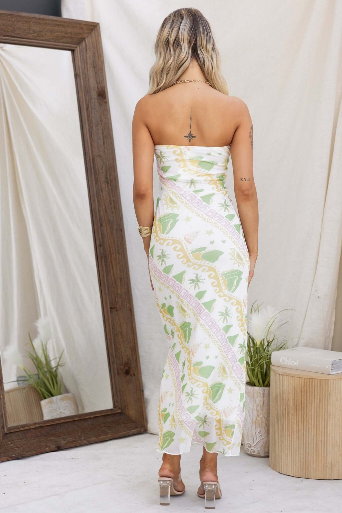 Back view of a woman wearing a strapless Orinzo Maxi Dress with a green and pink pattern.