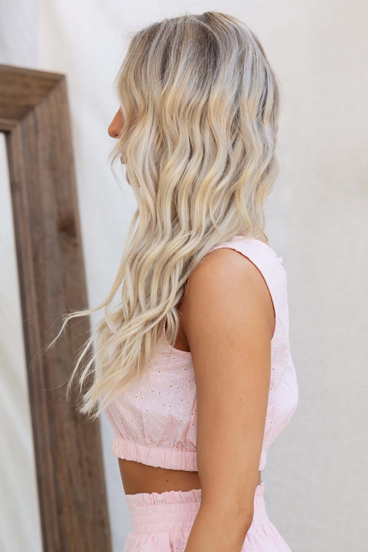 Side view of a model wearing the pink Ebba Top, showcasing its button back and elastic waistband.
