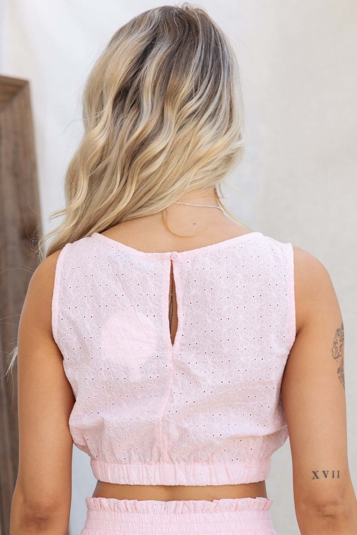 Back view of Ebba Top in soft pink with button closure and elastic waistband, showcasing a casual summer style.