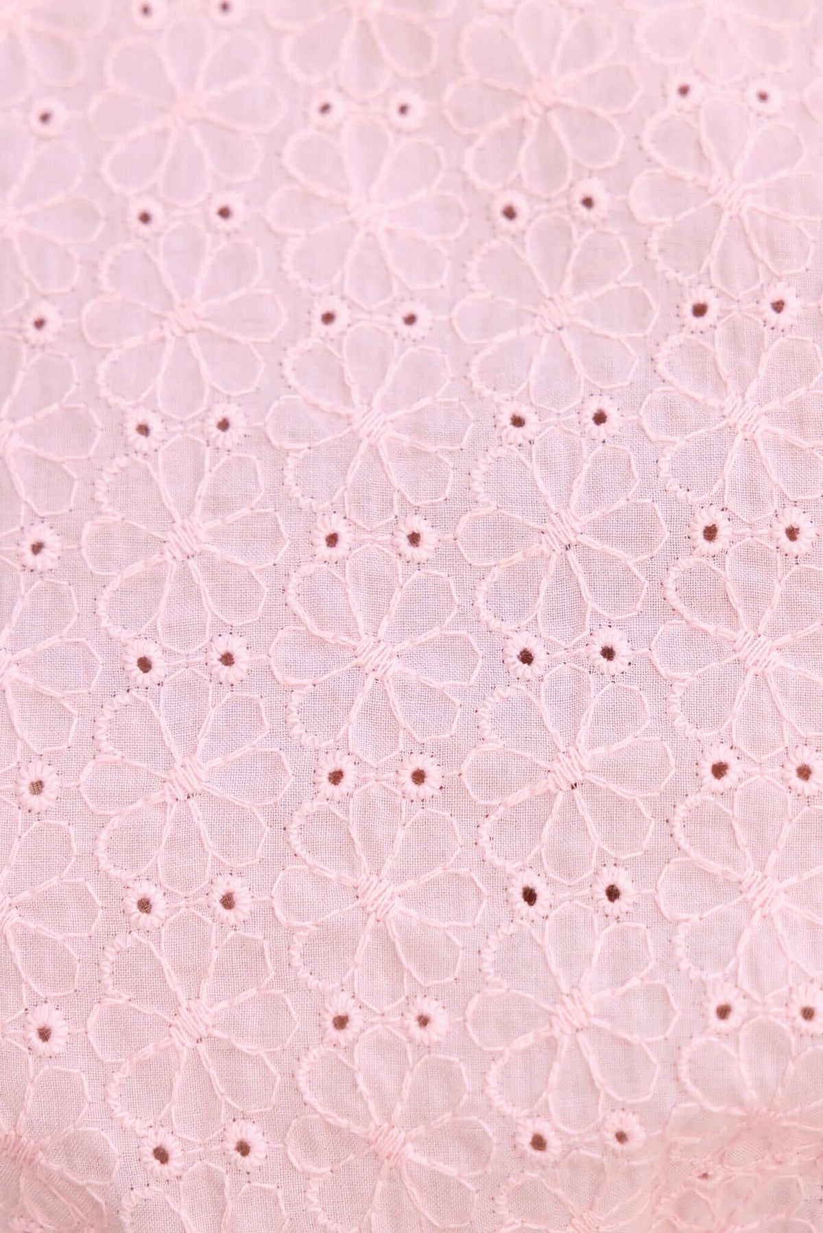 Close-up view of delicate pink fabric featuring intricate floral embroidery patterns.