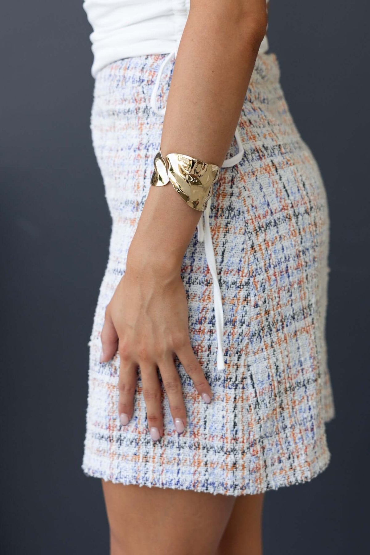 Side view of Tahina Skirt featuring a colorful textured fabric and mid-high waist fit, styled with a golden bracelet.