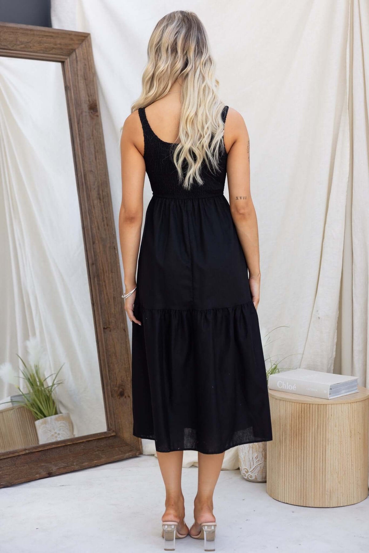 Back view of a woman wearing a black Haidy Midi Dress with elastic bodice and tiered hem.