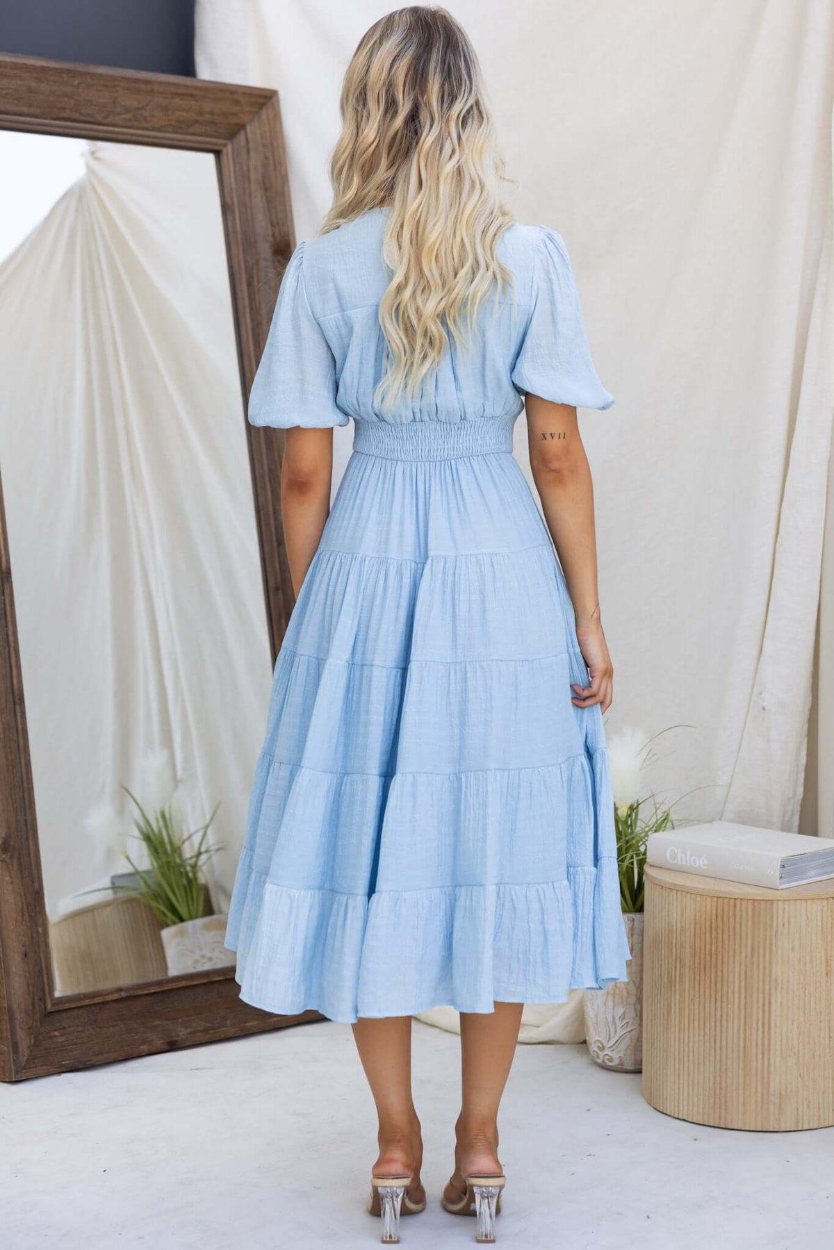 Bindi midi dress in blue, featuring a tiered design and puff sleeves, showcased from the back.