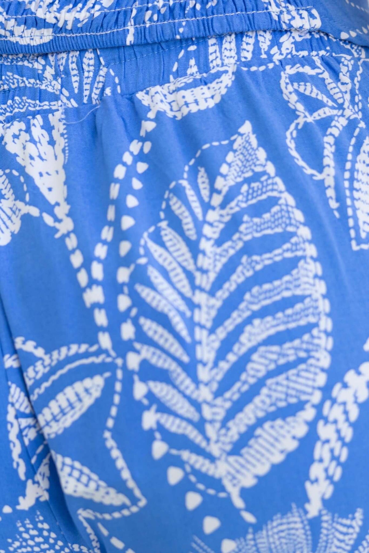 Close-up of blue fabric featuring white leaf pattern, showcasing the texture and design of the Lasan Set.