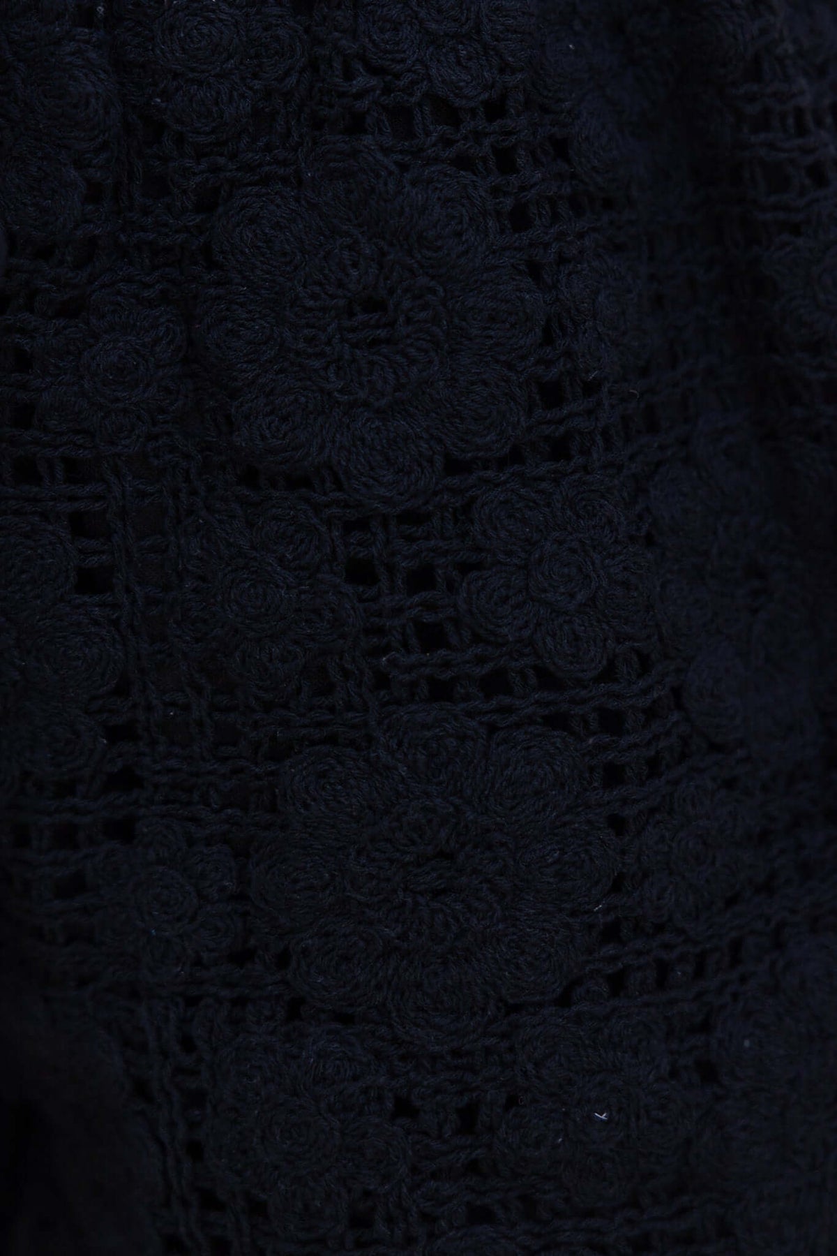 Close-up of black floral lace fabric, showcasing intricate patterns and textures, ideal for stylish tops.