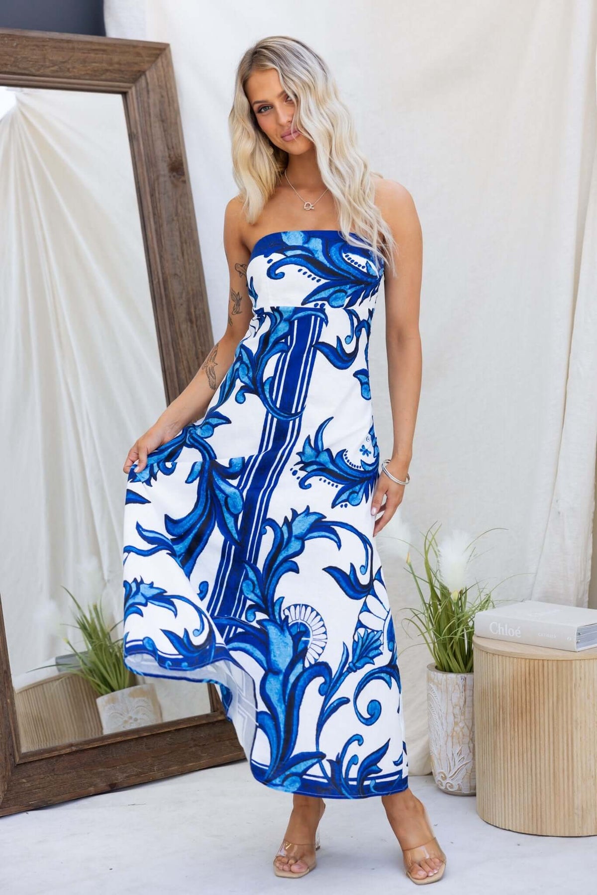 Model wearing Montclair Maxi Dress in blue and white patterns, showcasing a strapless, linen-like design with a flowing fit.