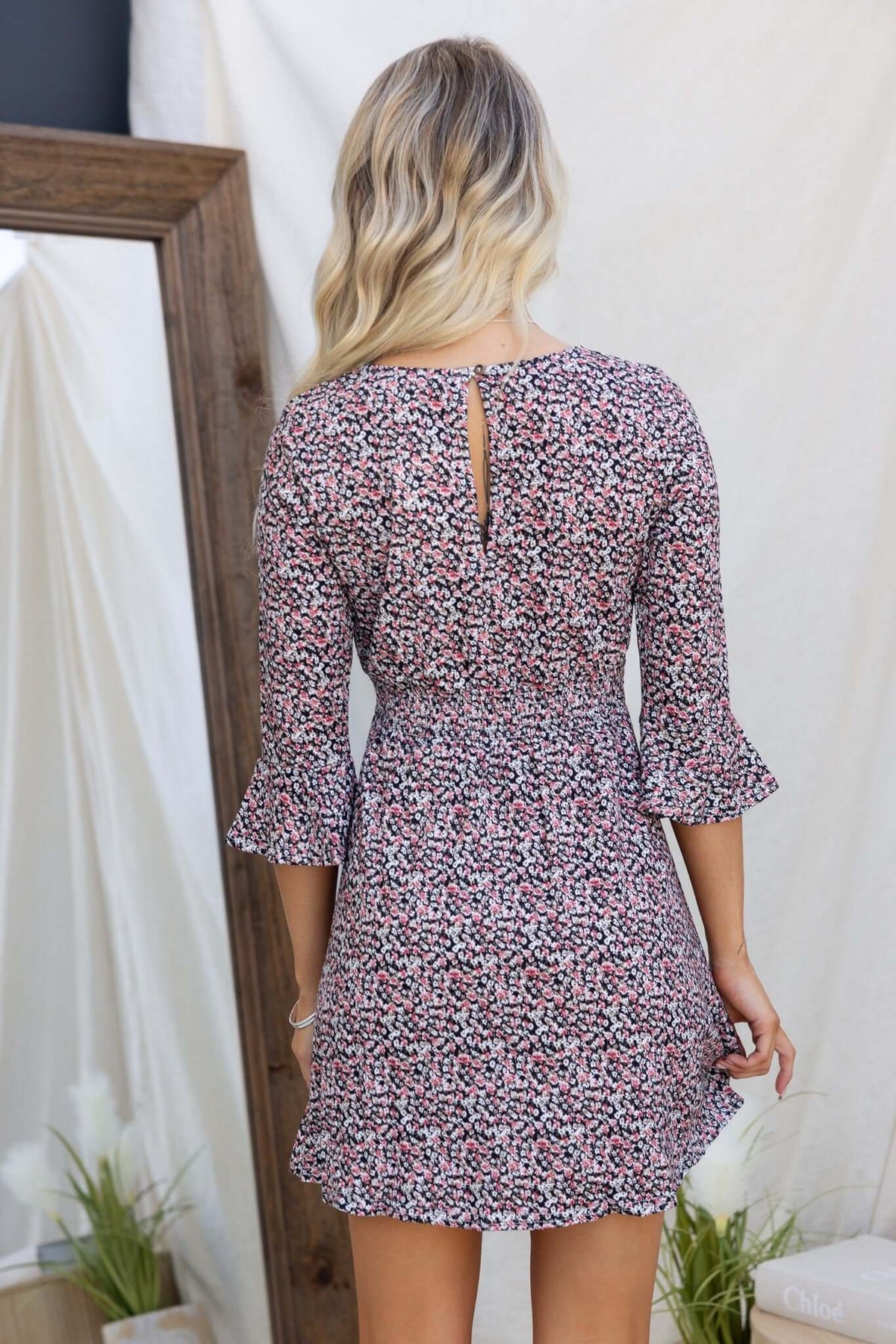 Back view of Darien Dress showcasing a floral pattern, flared sleeves, and button detail at neckline.