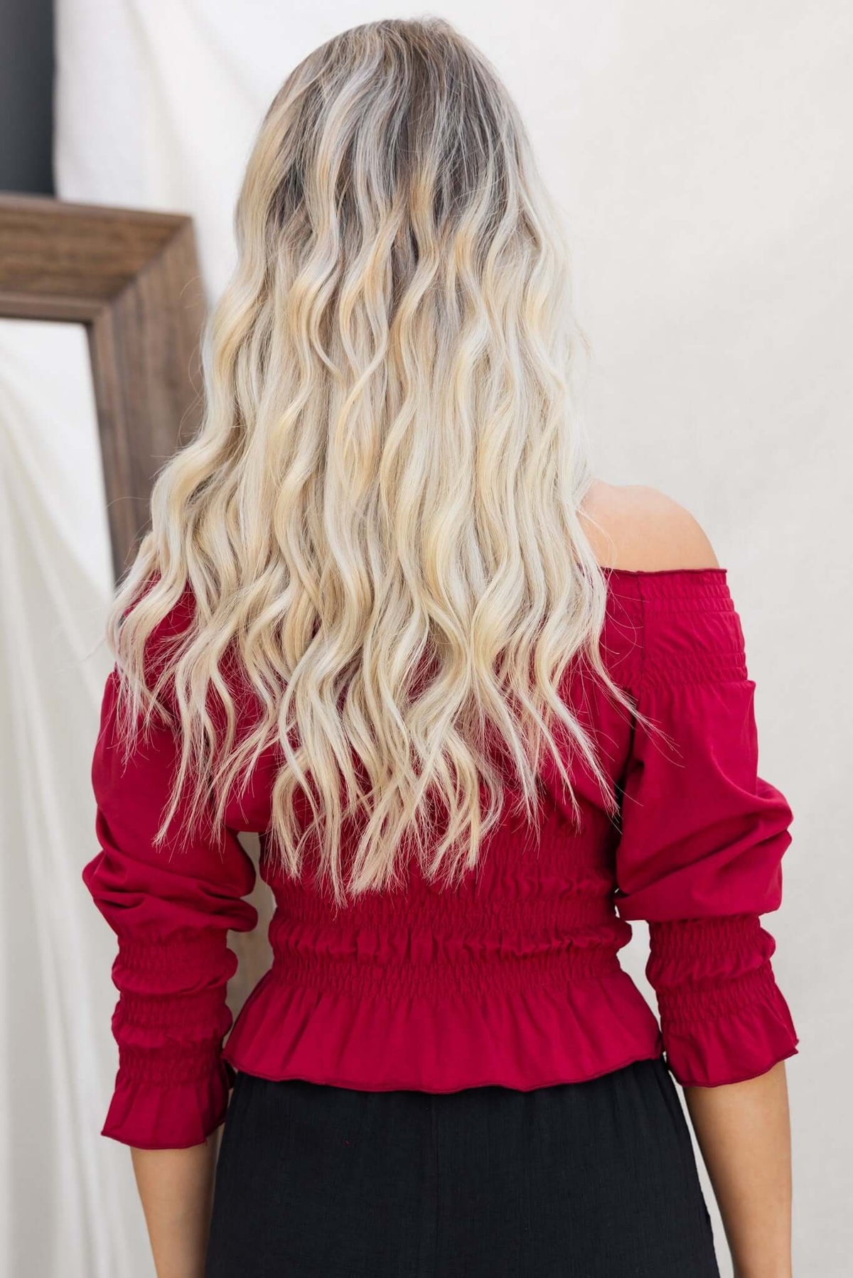 Back view of a woman wearing a red off-shoulder Jakari Top, showcasing its smocked design and flowy fit.