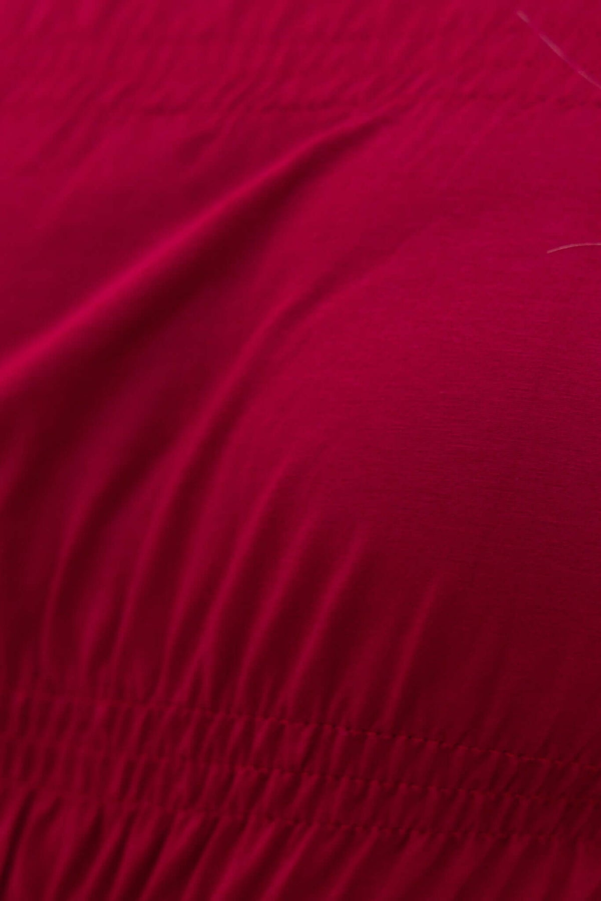 Detail view of the Jakari Top in vibrant fuchsia, showcasing the off-shoulder elastic fabric texture.