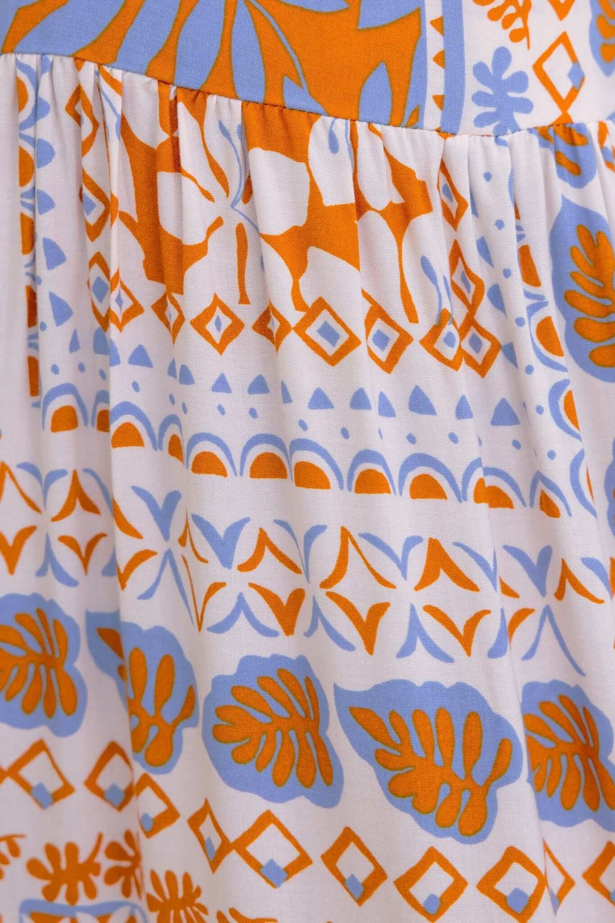 Close-up of Dapple Maxi Dress fabric featuring vibrant orange and blue floral and geometric patterns.