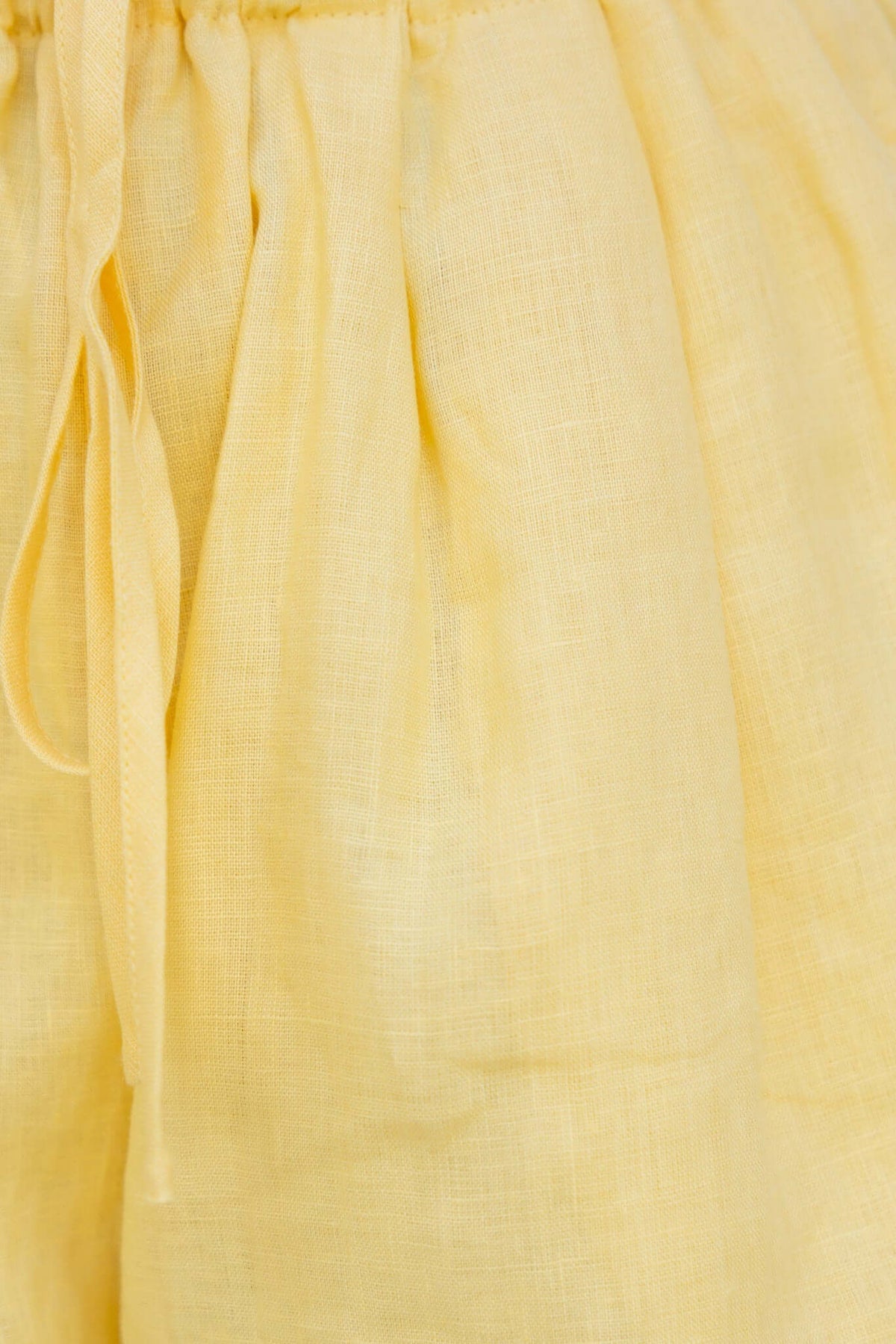 Close-up of Orson Shorts in yellow linen, featuring an elastic waistband with drawstring for comfortable fit.