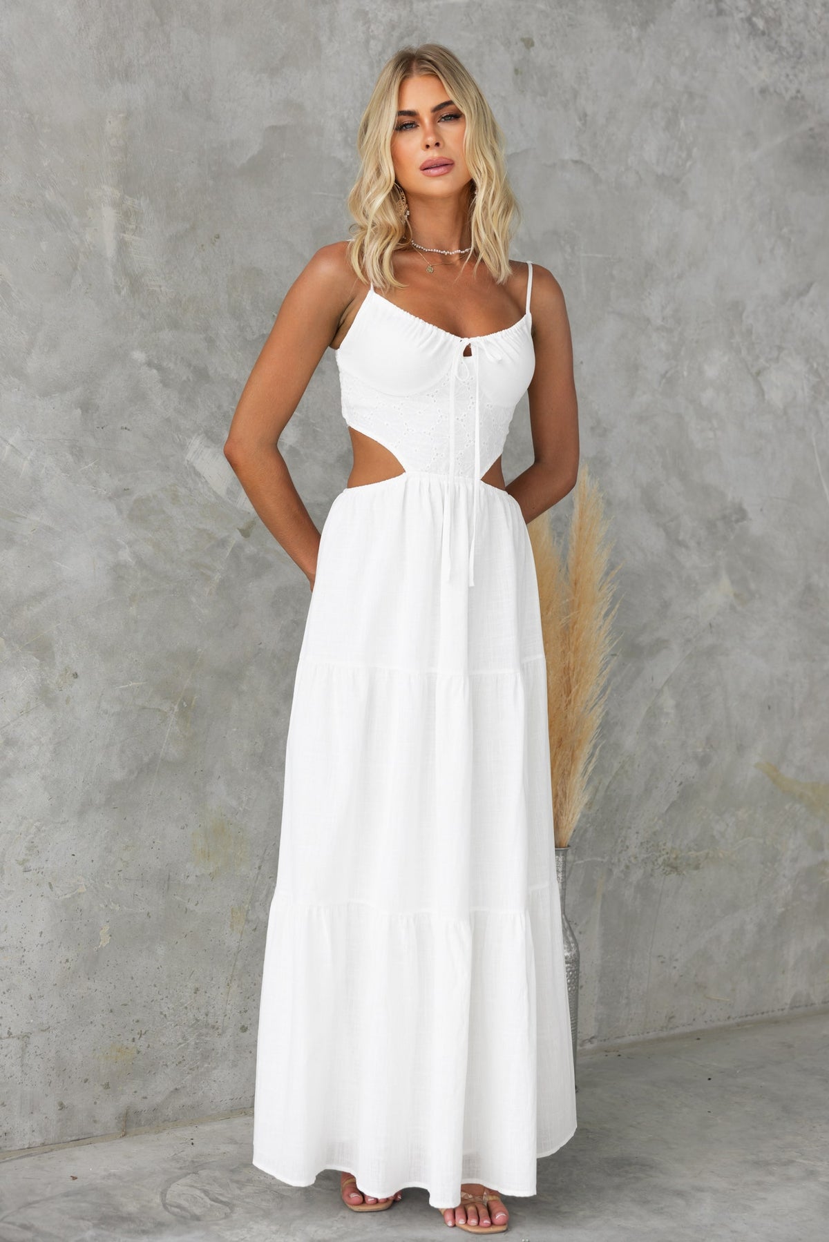 Model wearing Noya Maxi Dress, a white cut-out maxi dress with adjustable straps and tie detail.
